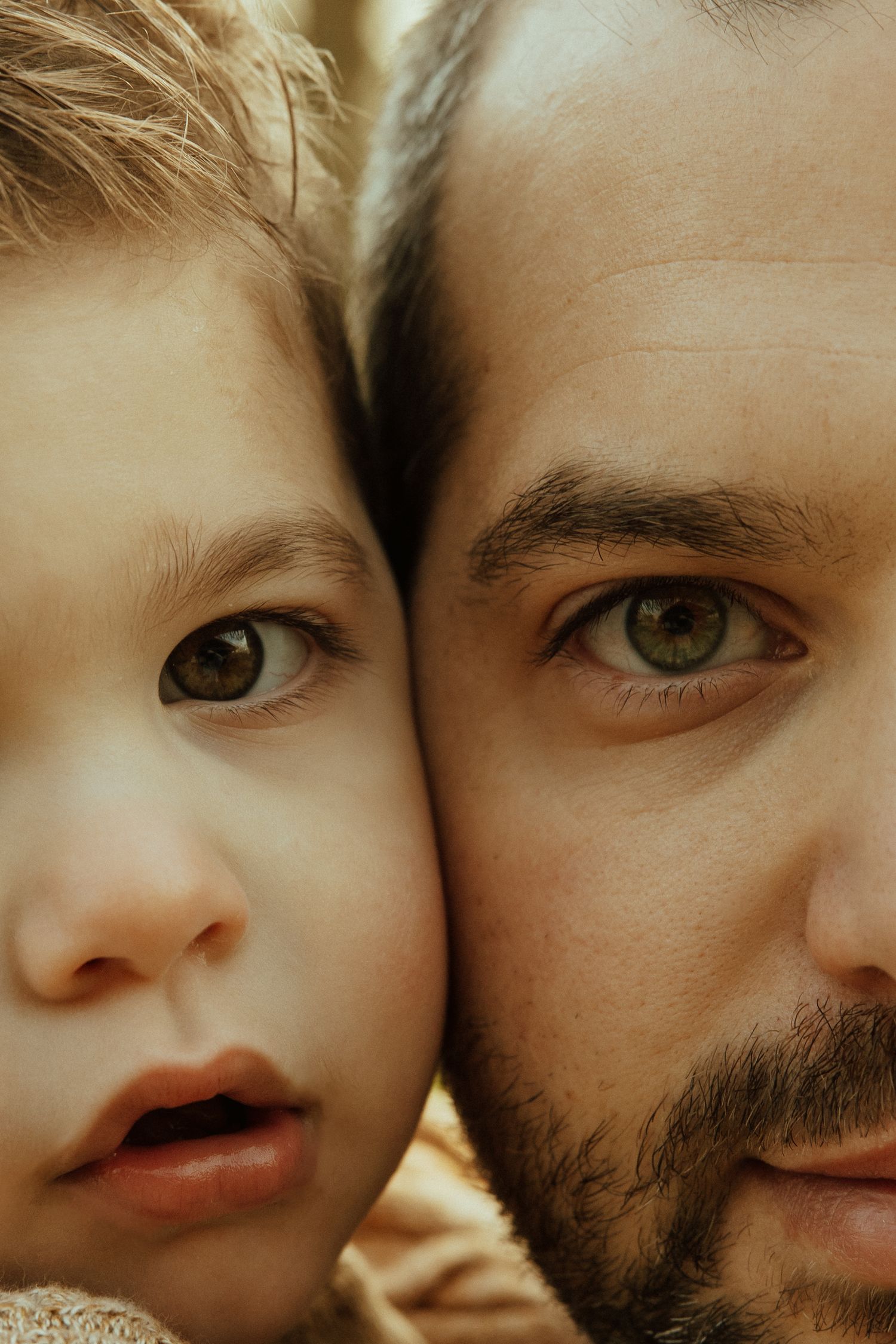 Close-up portrait showing half faces side by side with matching green eyes in warm lighting.
