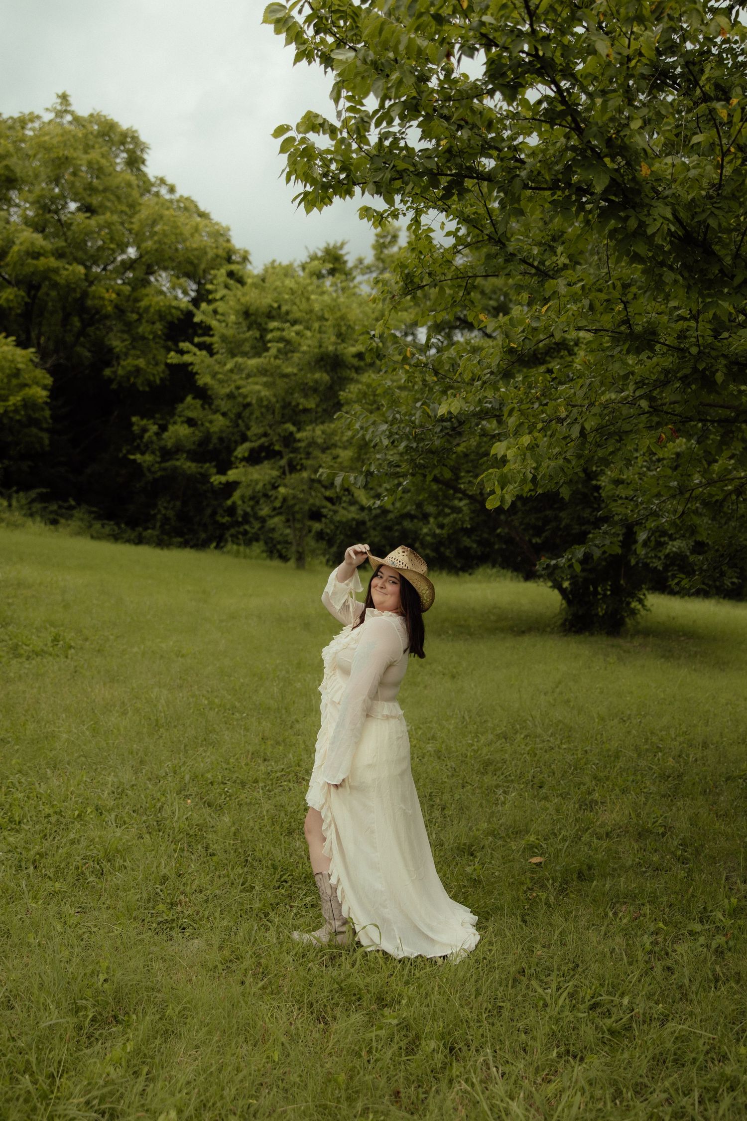A romantic outdoor photoshoot in a green field showing intimate moments in flowing white dresses.