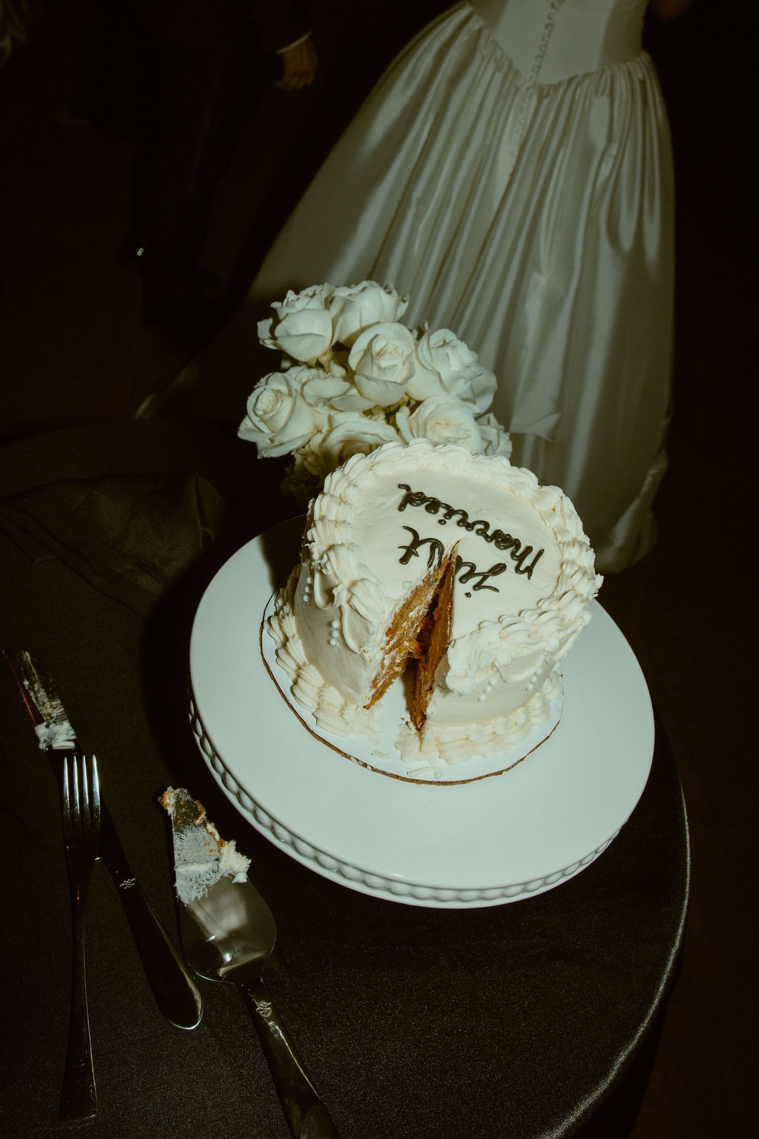 A white wedding cake with floral decorations being cut into slices.
