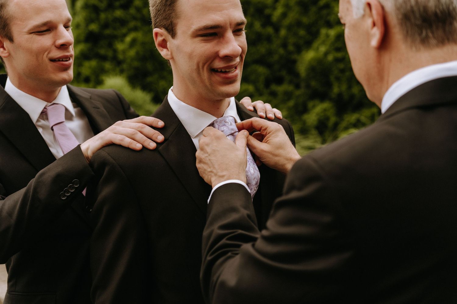 Candid black and white wedding photo showing guests in formal attire laughing during an outdoor reception.