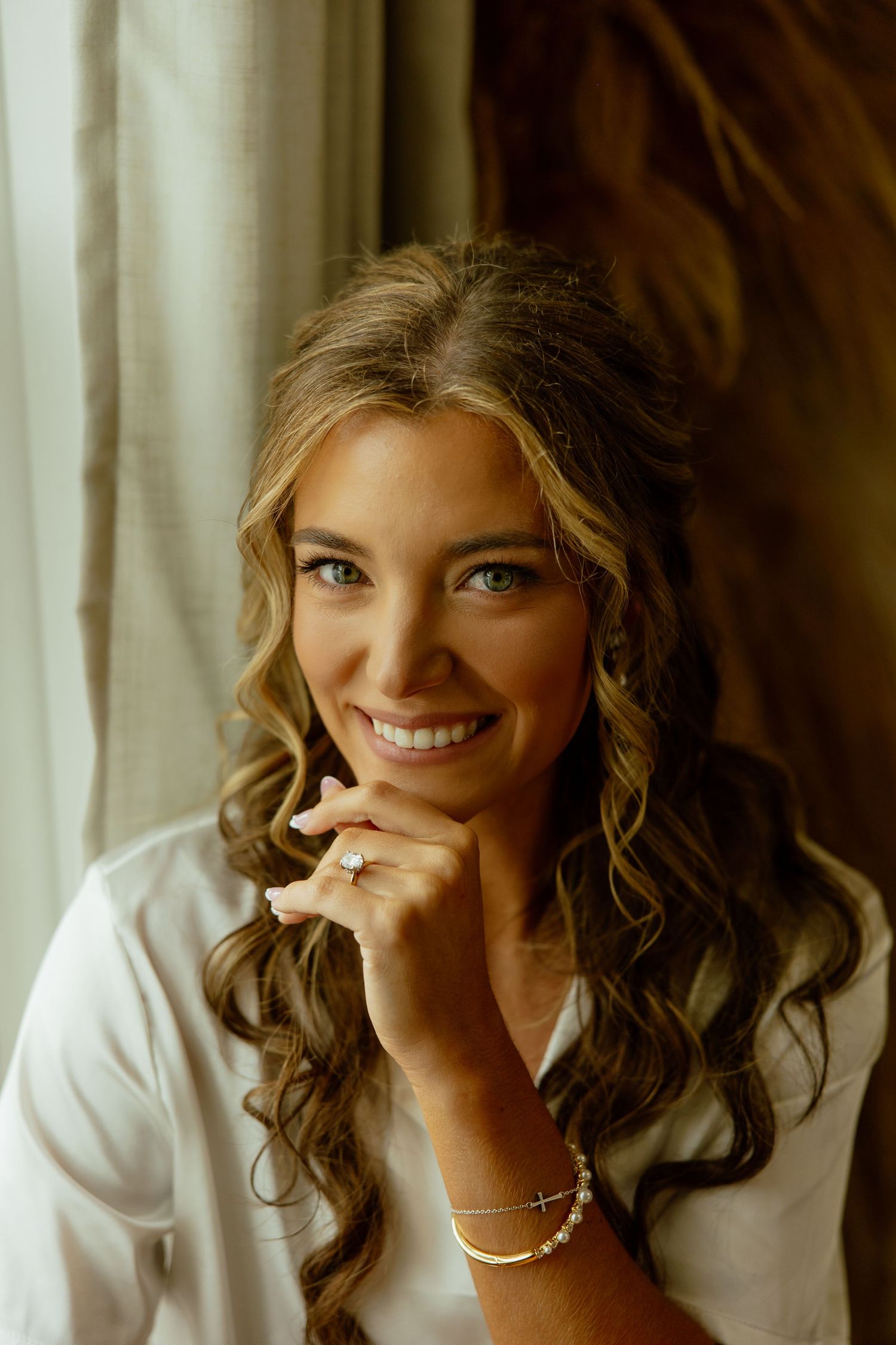 A series of portraits showing a woman with curly hair in a white top smiling and posing against a light background.