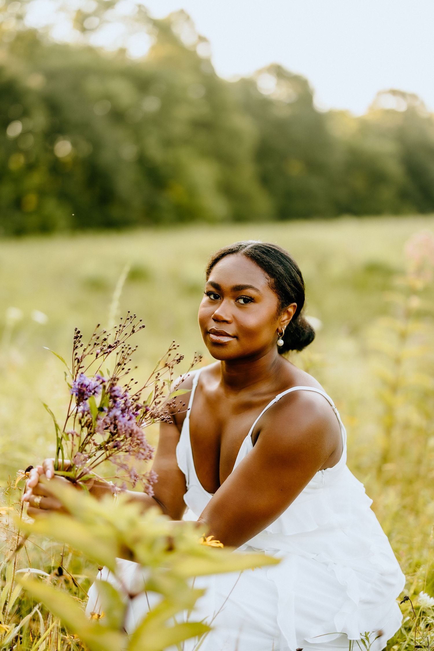 A serene summer portrait in a wildflower field with a white dress and delicate purple blooms.