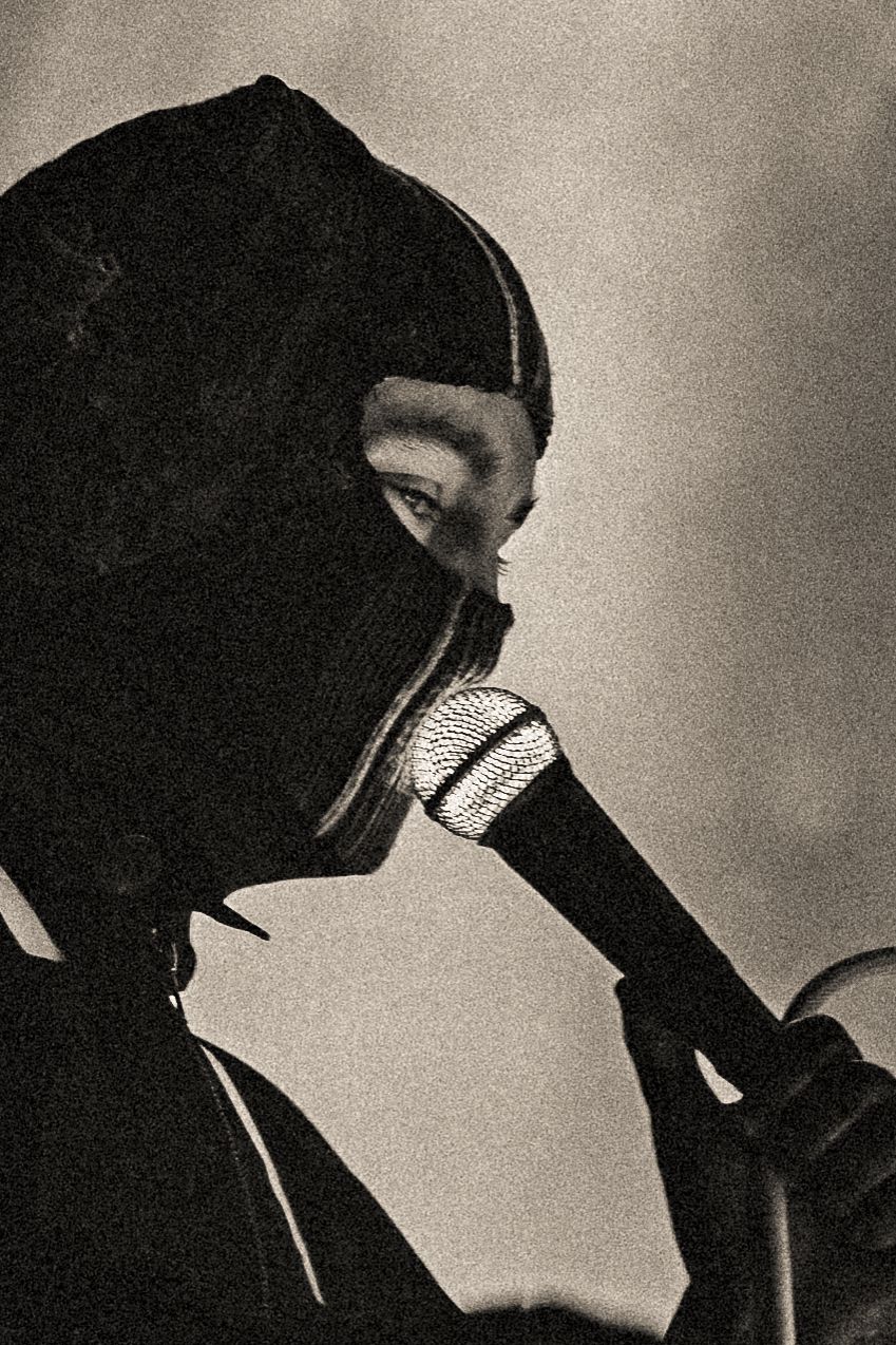 Artistic black and white portrait of performer with microphone wearing balaclava.