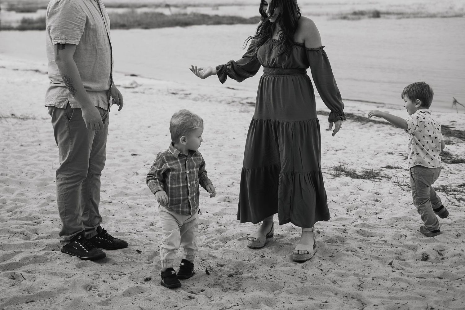 Family enjoying a casual walk together on the beach in black and white.