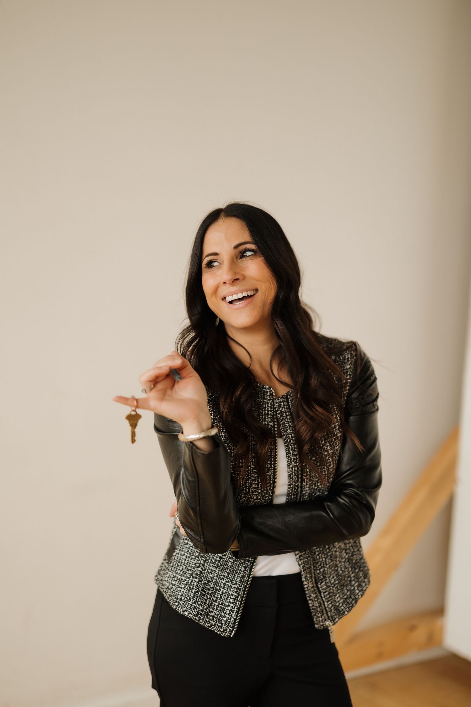 Joyful portrait in textured jacket with confident expression against beige wall.