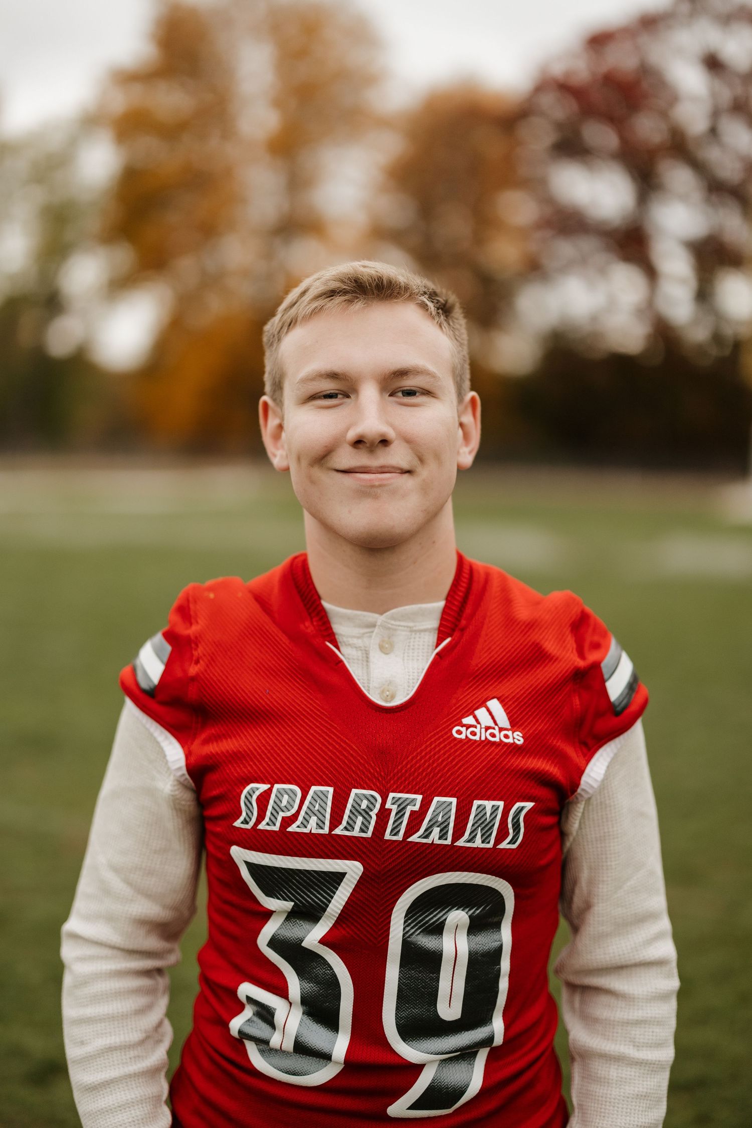 Spartans football player wearing red jersey number 39 poses on field.