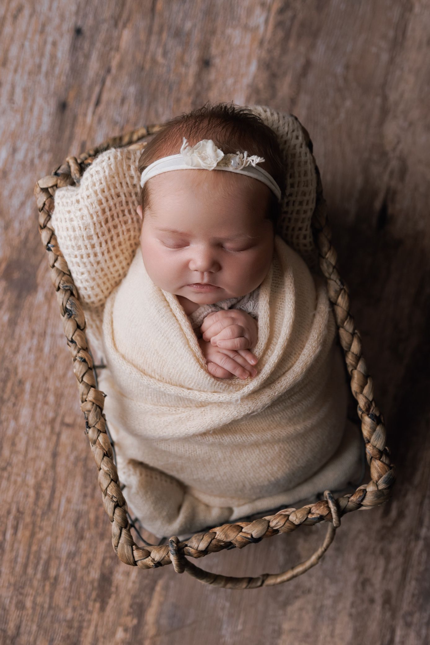A sweet newborn baby girl peacefully nestled in a cozy basket, wrapped in soft blankets and surrounded by gentle light.