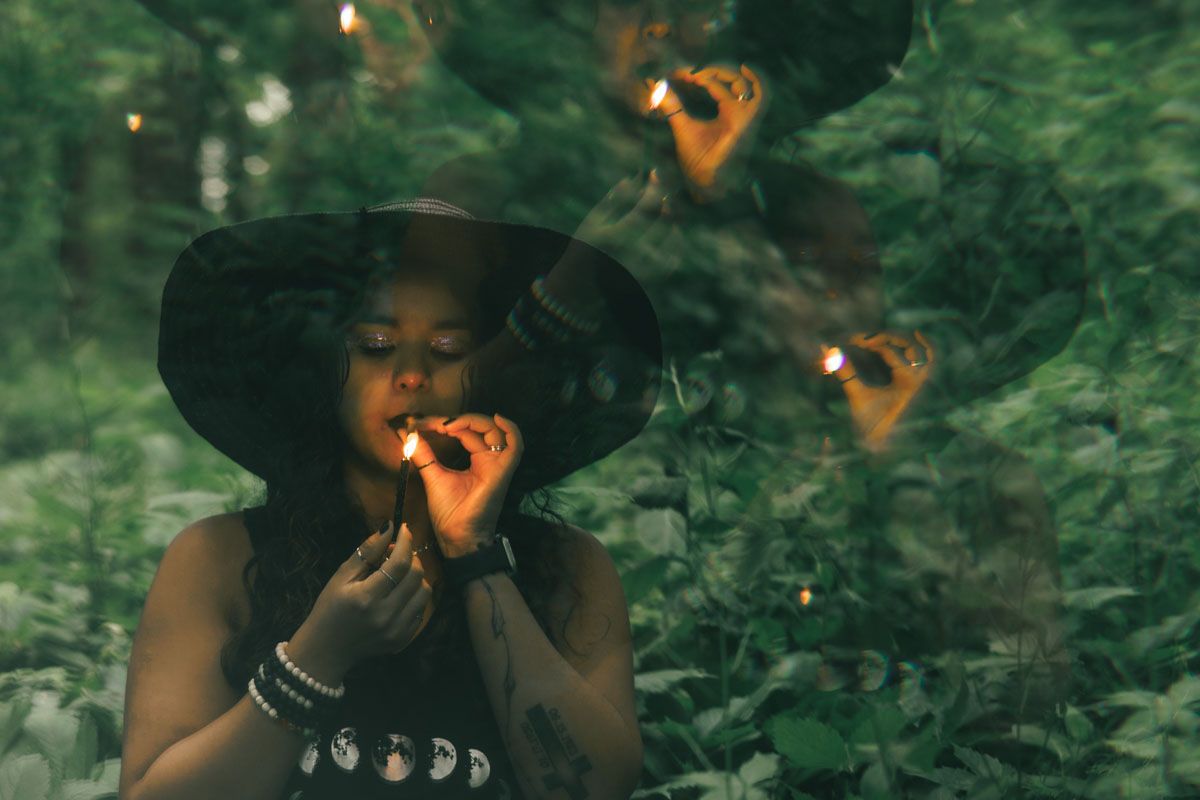 A mystical forest scene with floating orange lights and a figure in a wide-brimmed hat.