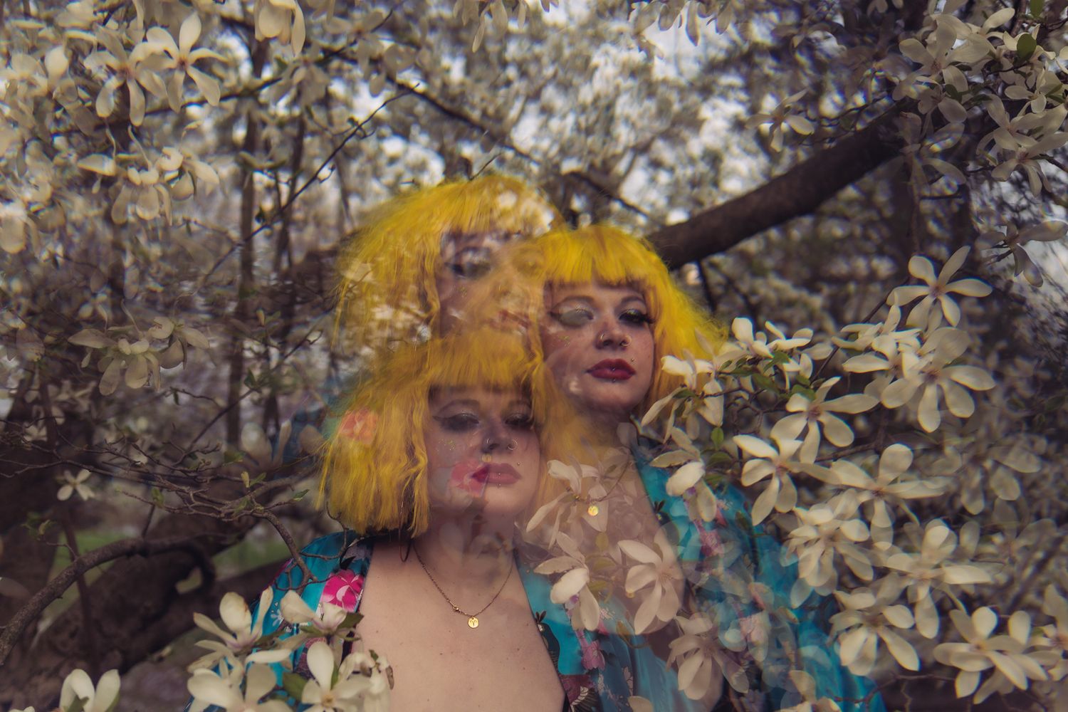Artistic portrait surrounded by white flower blossoms and branches with dramatic lighting.