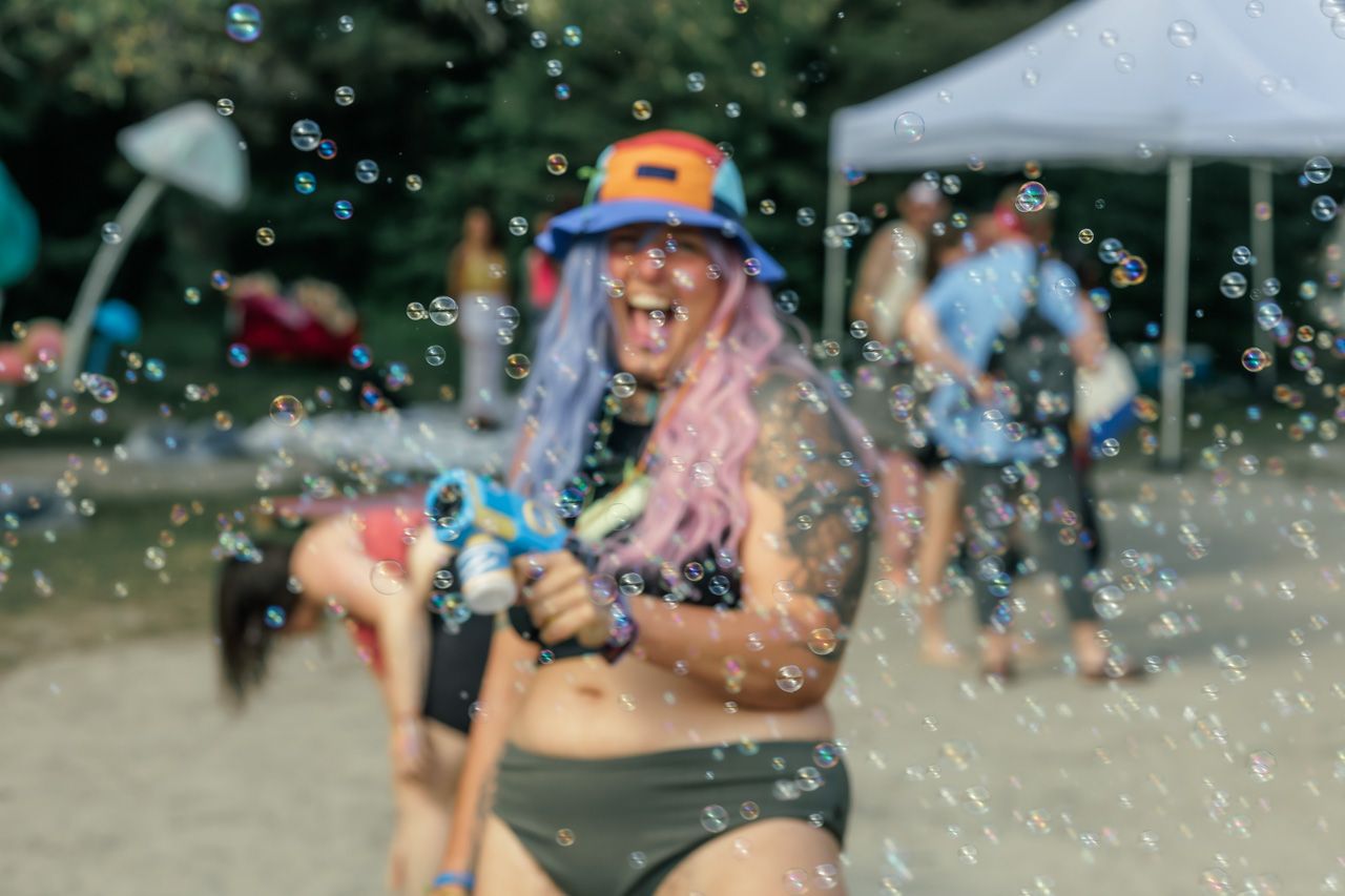 People enjoying a summer celebration with bubbles and water splashing at an outdoor event.