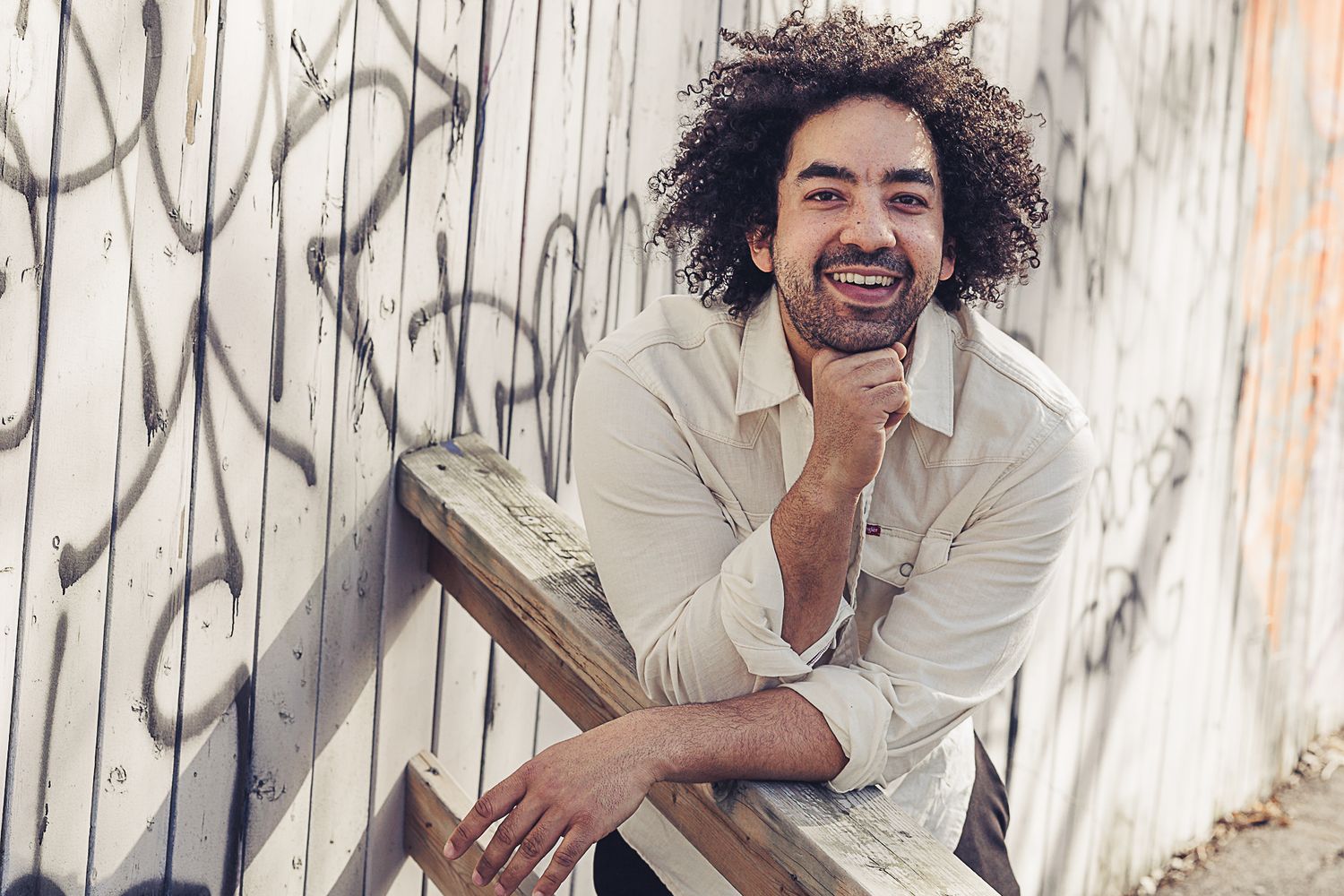 A casual portrait against a graffiti wall showing joy and laughter.