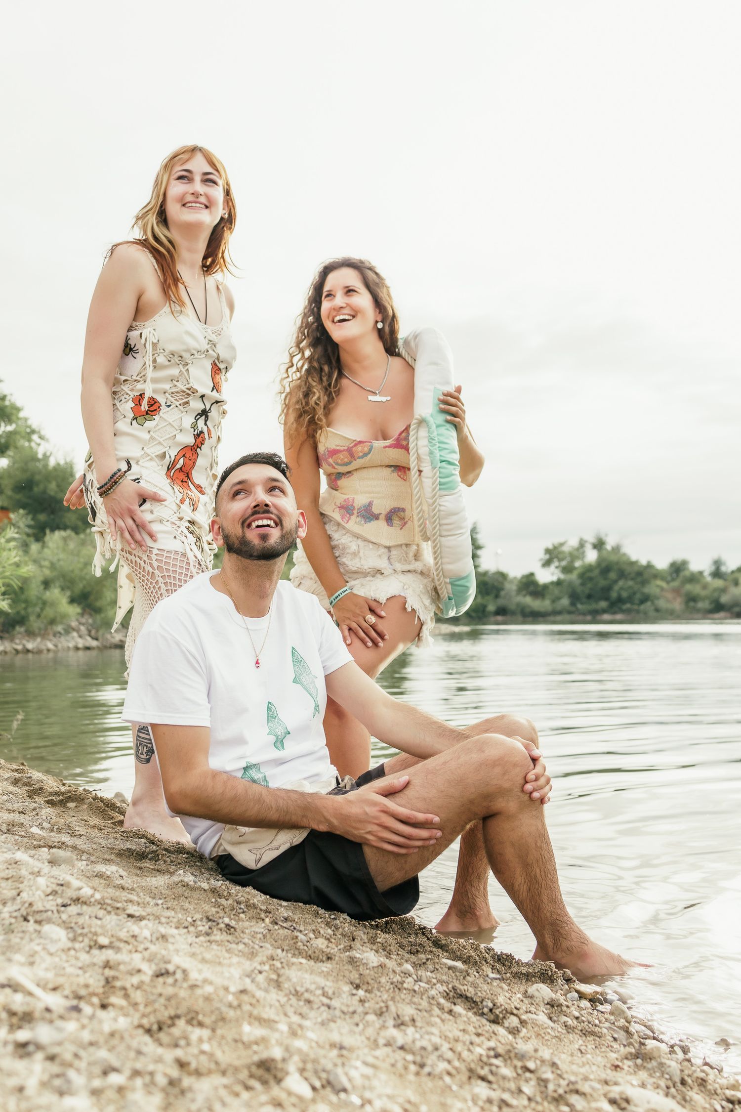 Editorial style small group shot sitting by the water's edge on a sunny day.