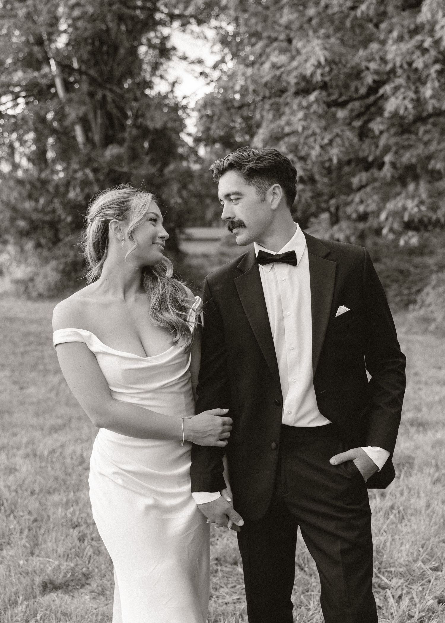Bride and groom share a tender moment gazing at each other in a black and white portrait.