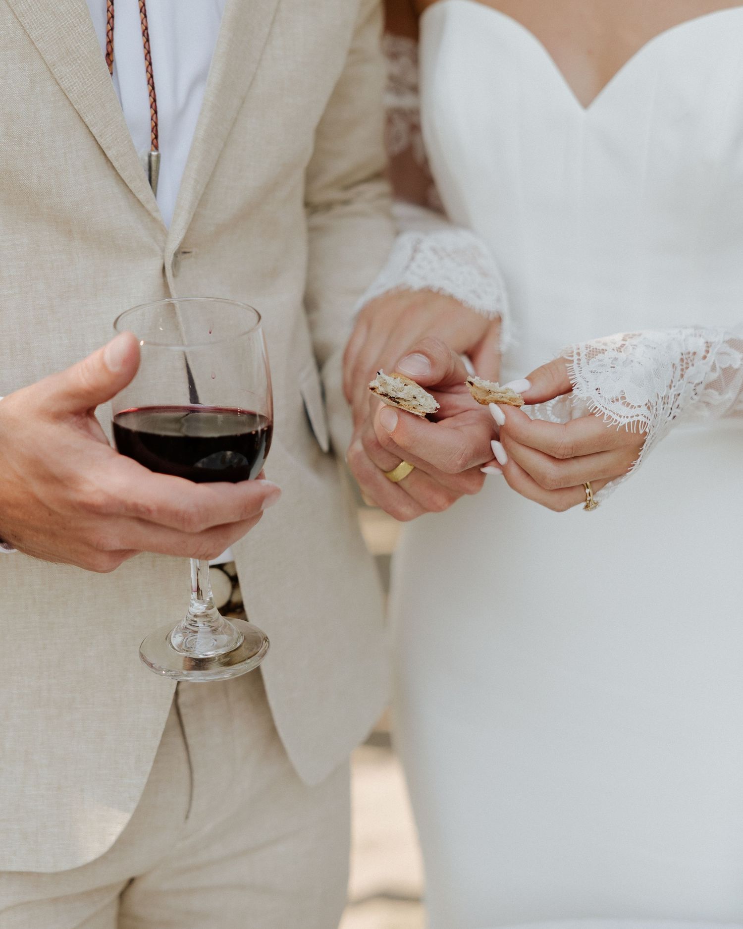 Close-up shot of couple holding wine glasses during wedding ceremony.