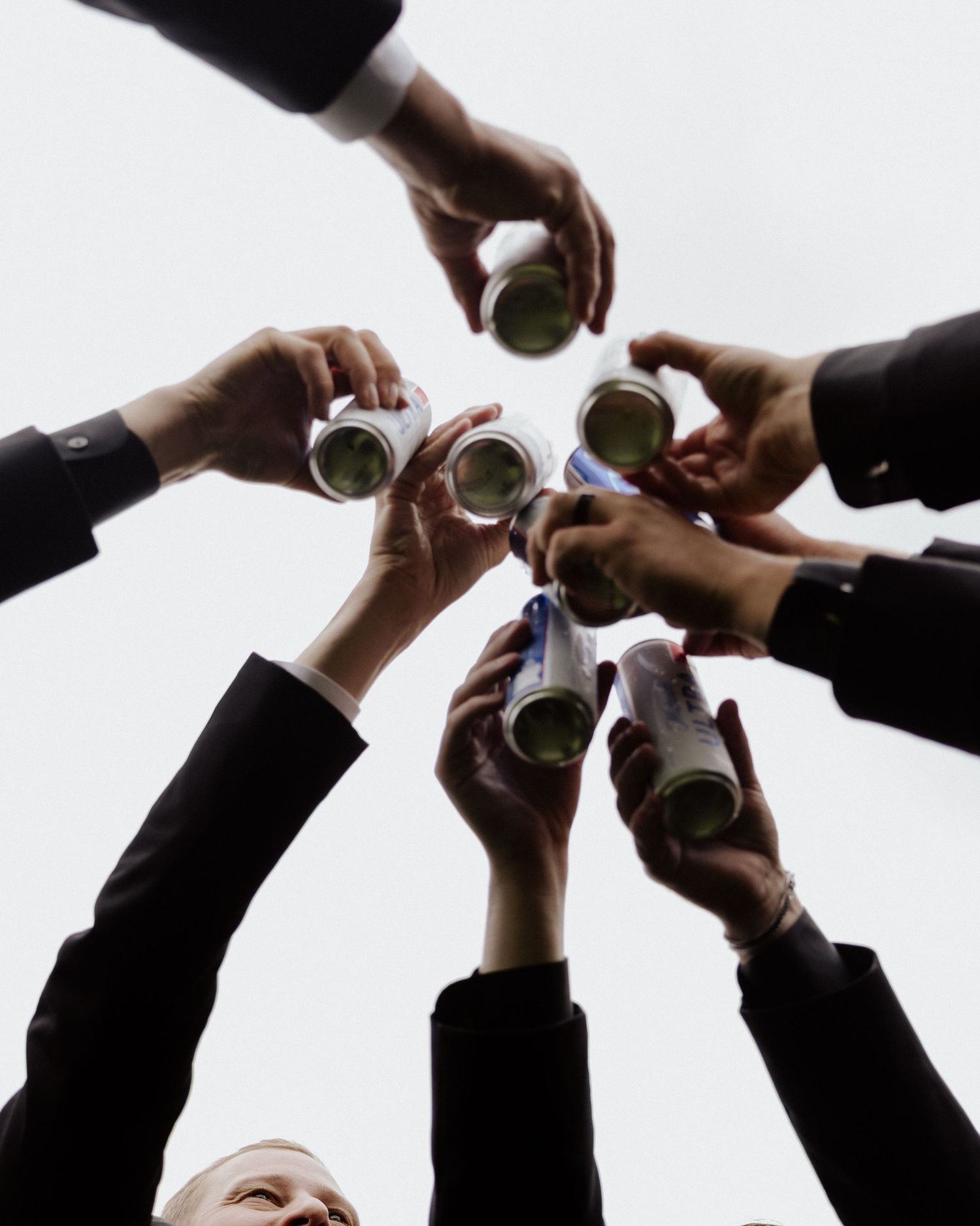 Hands raise champagne glasses in a celebratory toast against white background.