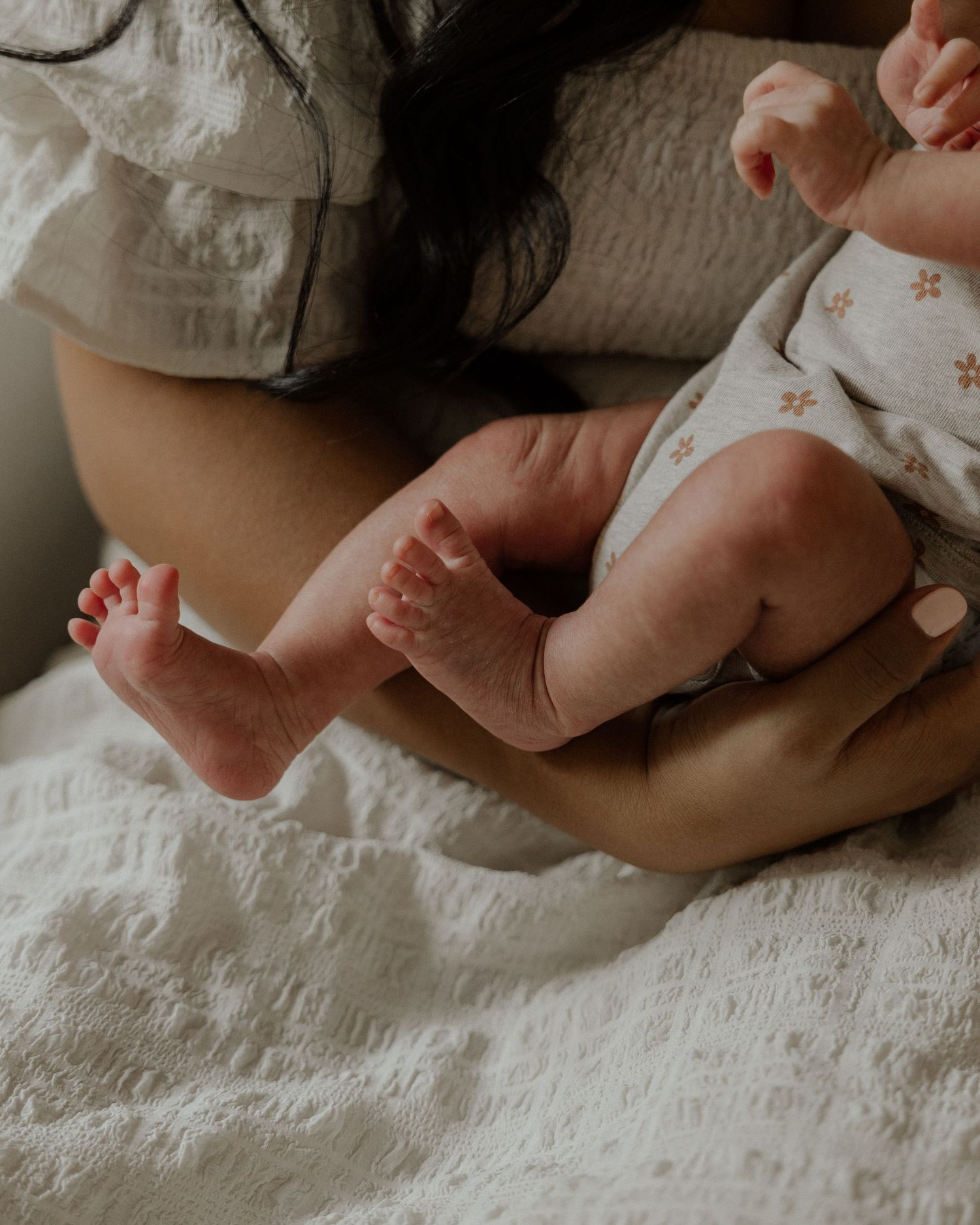 Close-up of tiny newborn baby feet resting on white bedding.