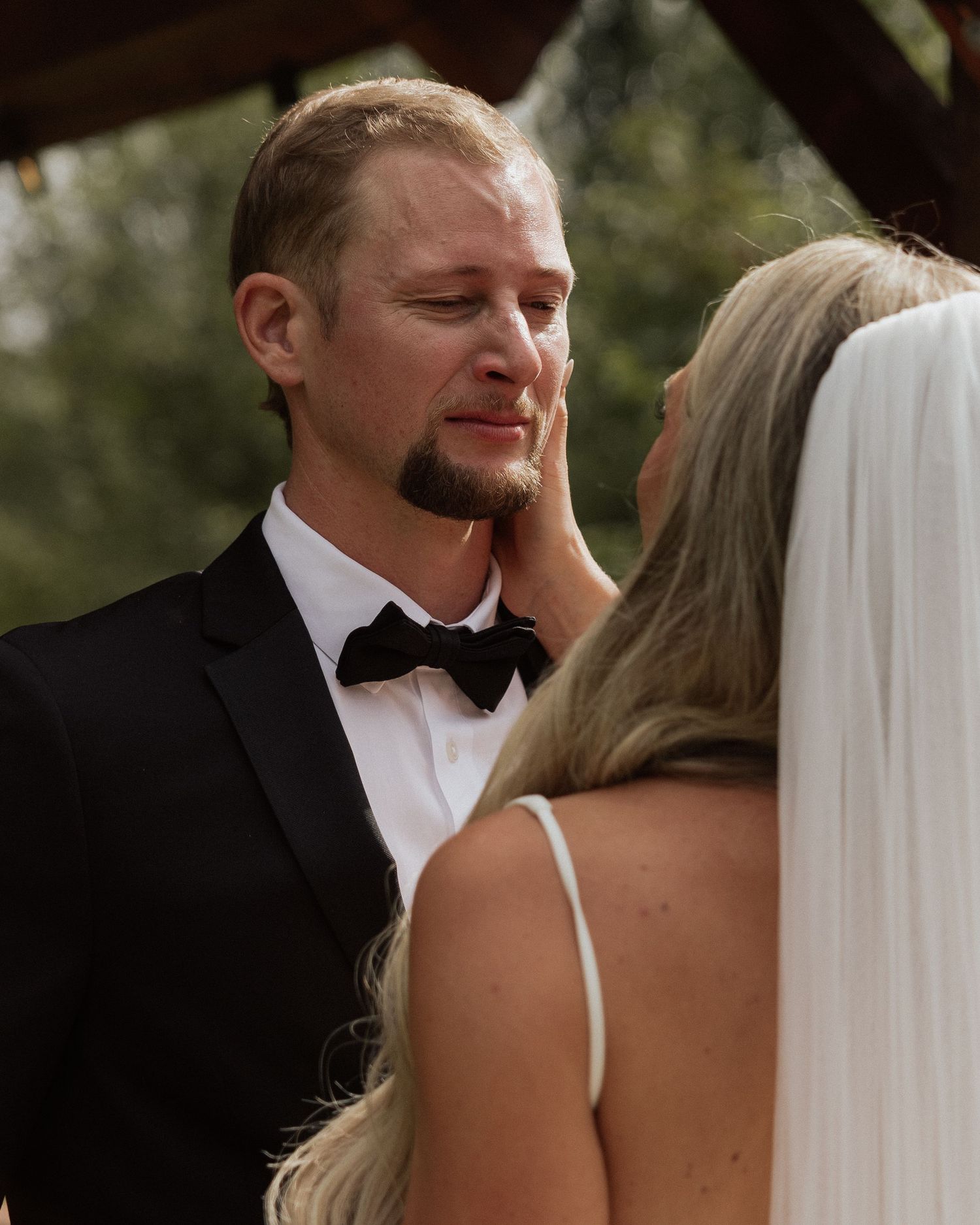 Emotional moment during wedding ceremony on wooden covered bridge.