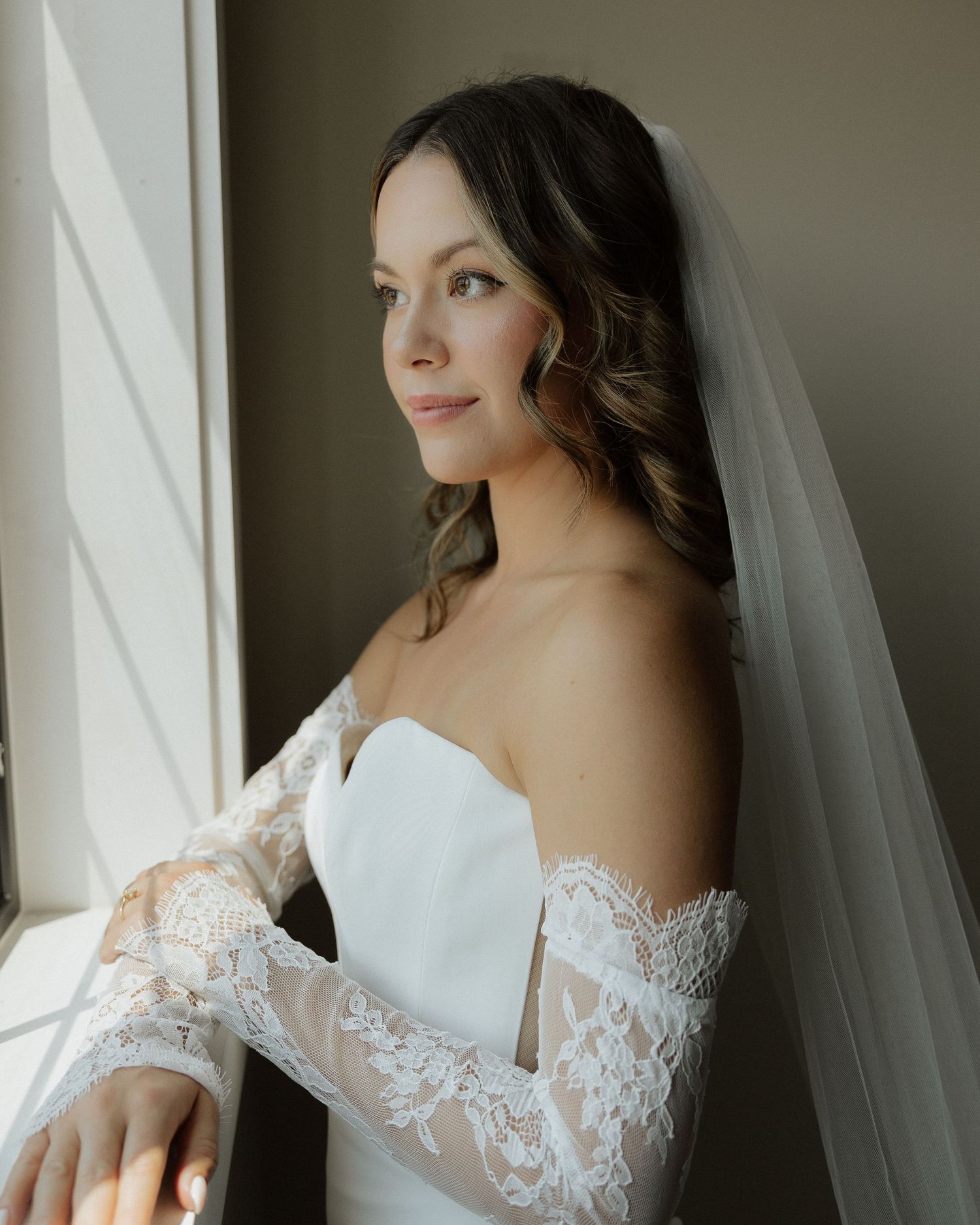 Elegant bridal portrait with soft window light and flowing veil.