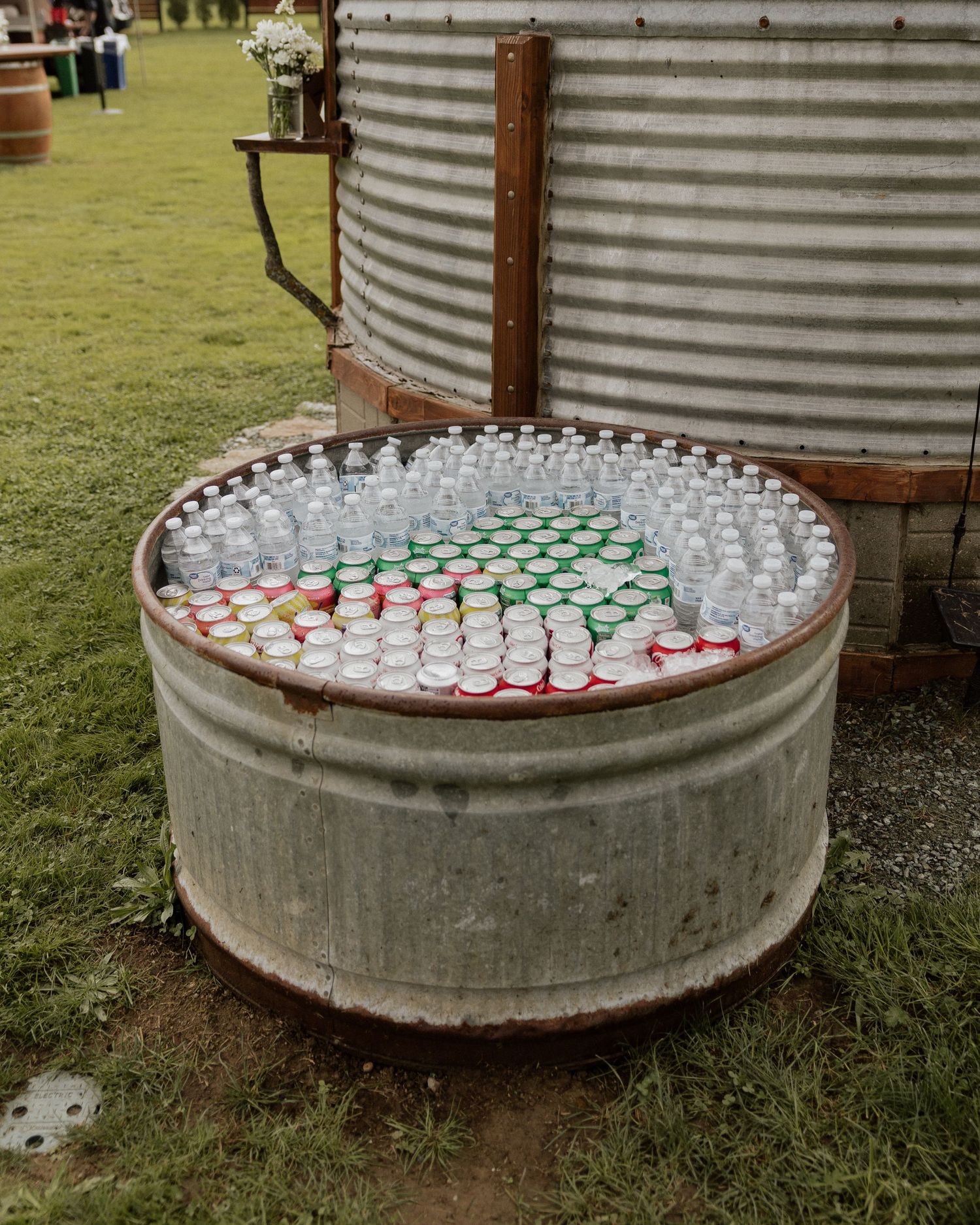 Drink station with arranged cups and beverages on metal drum cooler outdoors.