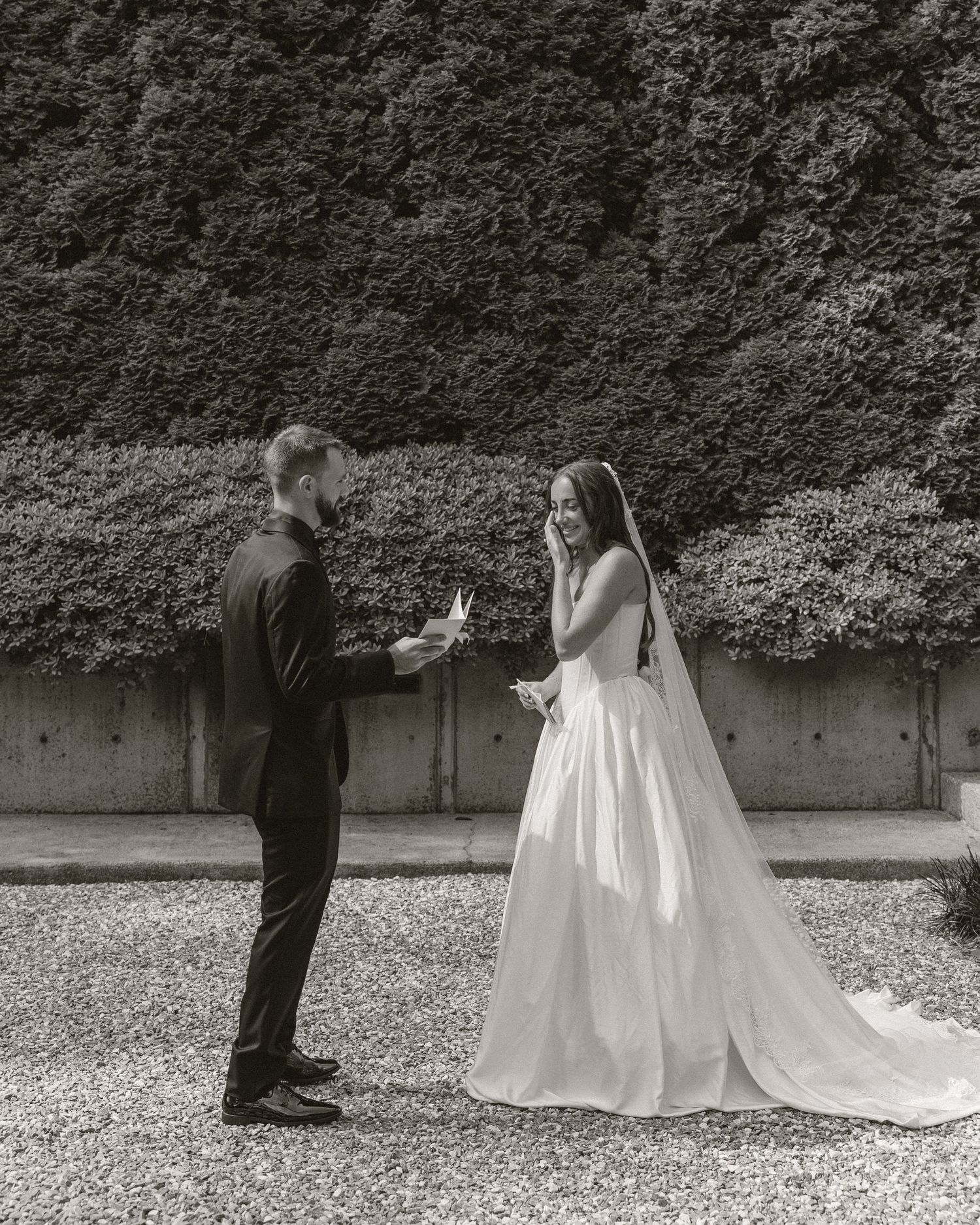 Bride and groom exchanging vows outdoors in black and white wedding photo.
