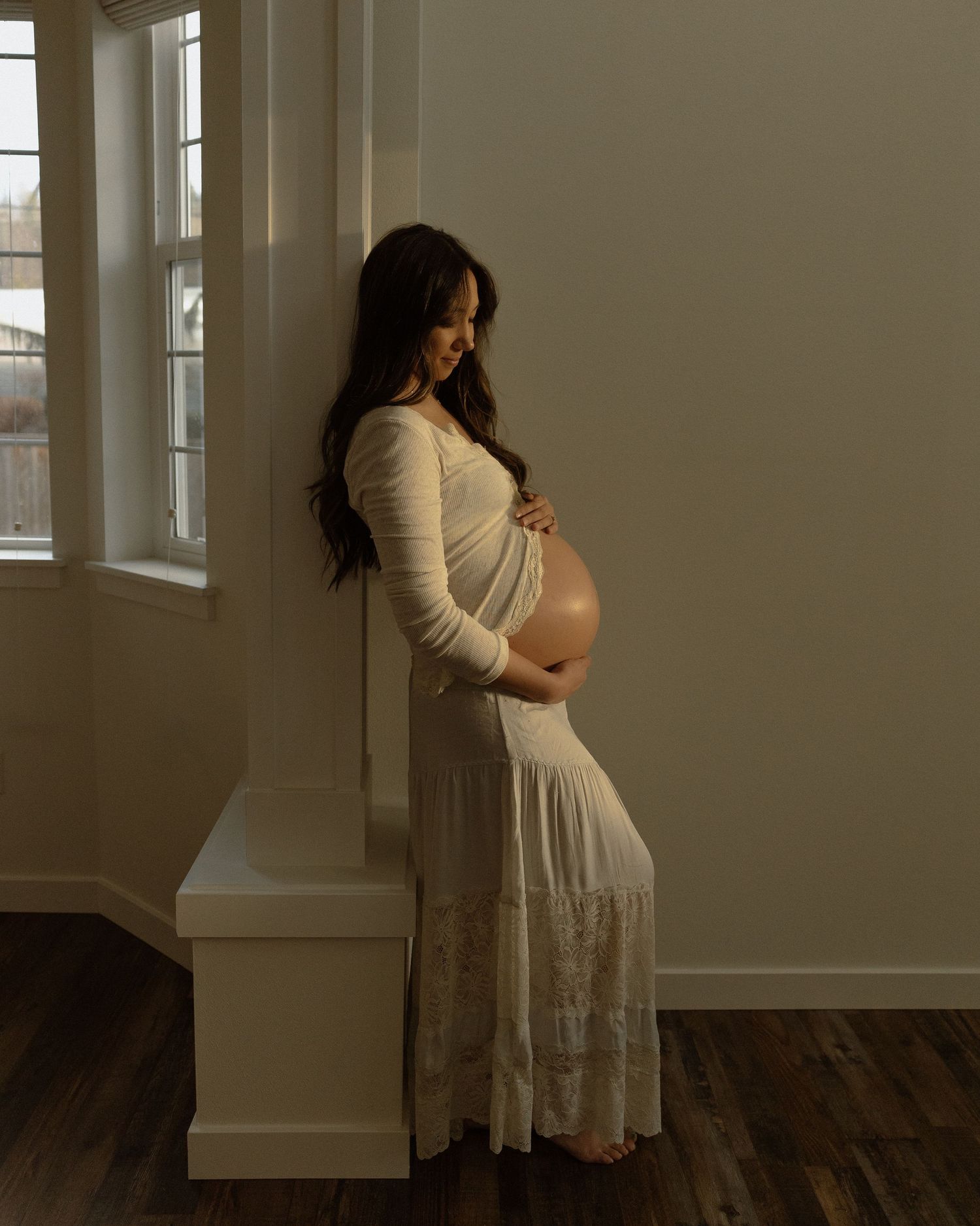 A peaceful maternity portrait of an expectant mother leaning against a pillar.