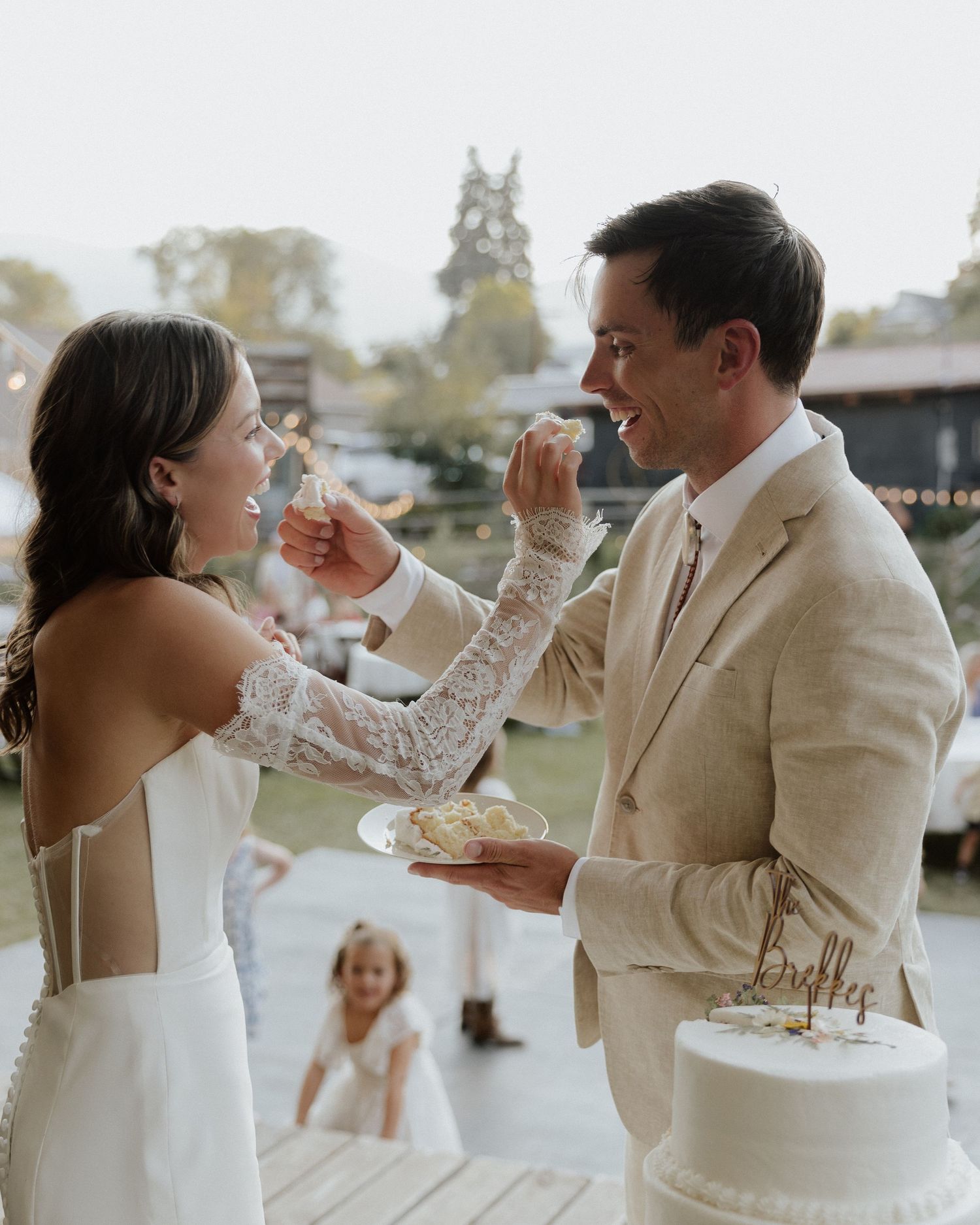 Wedding couple sharing cake during their outdoor reception celebration.