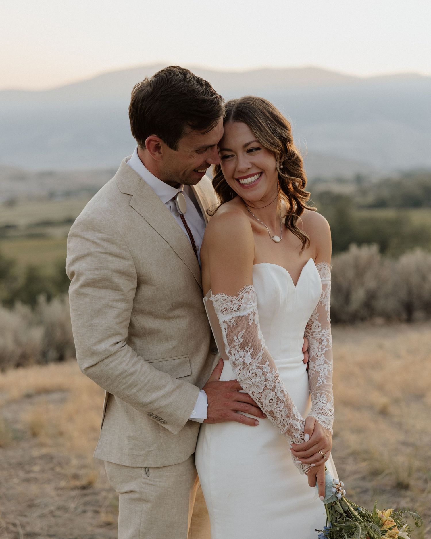 Joyful wedding couple shares intimate moment in desert setting during golden hour.