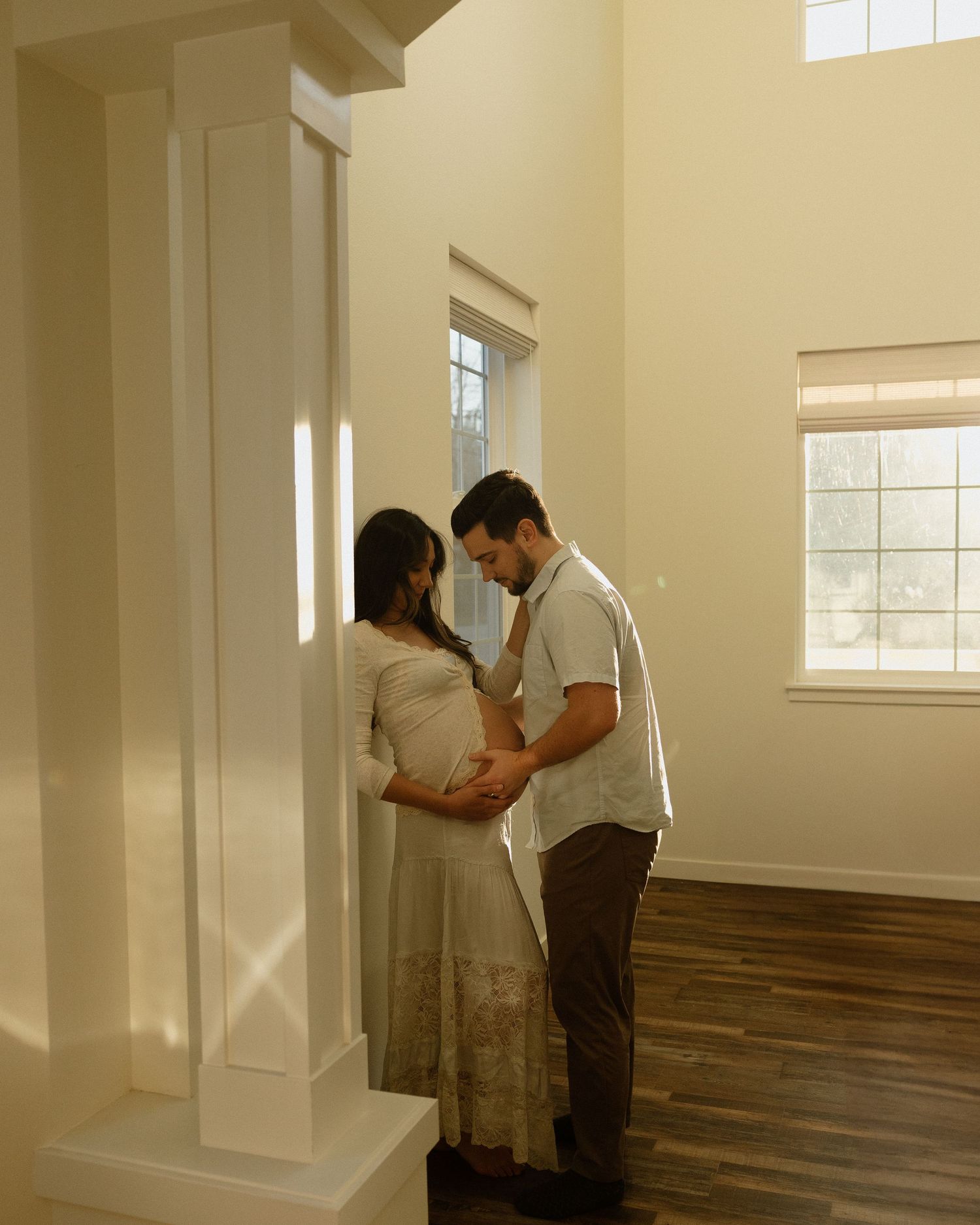 Natural light streams through windows during an intimate maternity photoshoot.