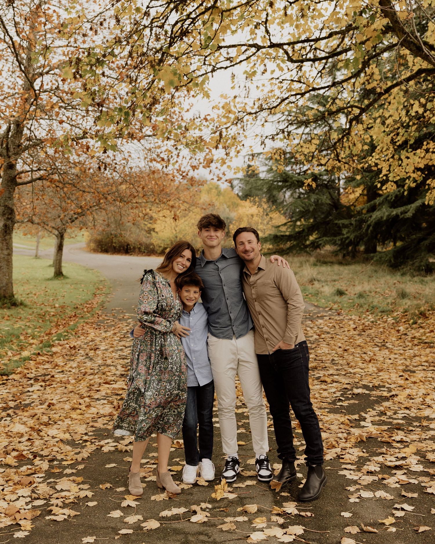 A smiling group stands together on a path covered in yellow autumn leaves.