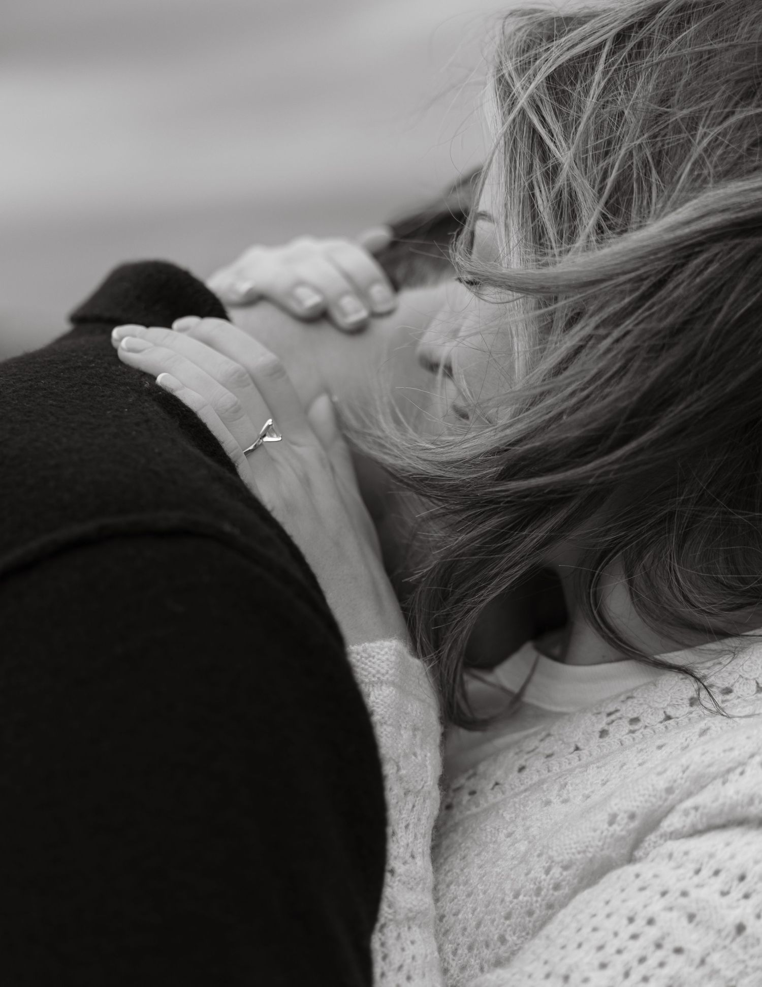 A close-up black and white photo showing an intimate embrace with a sparkly ring visible.