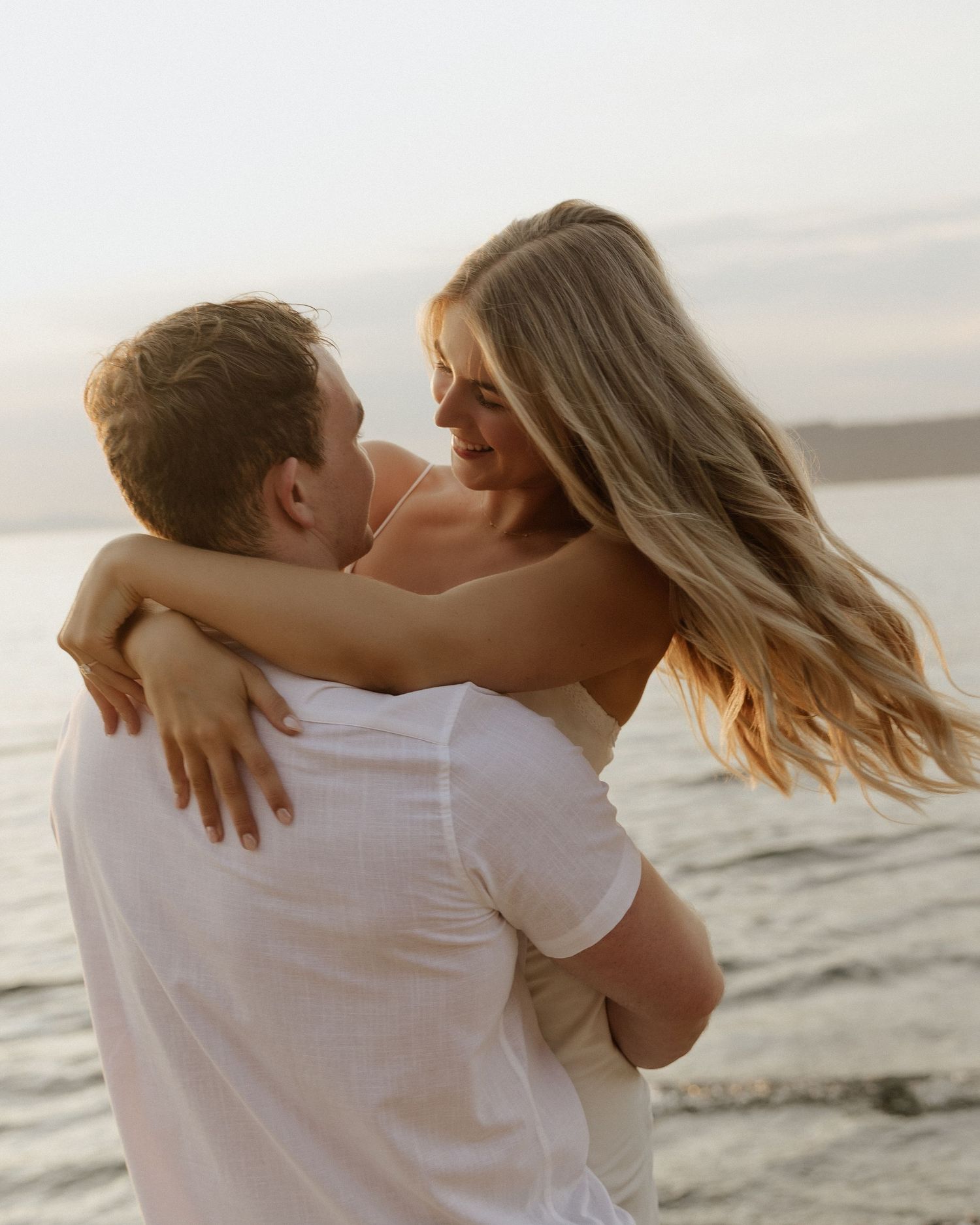 Joyful couple embracing and laughing together on sunset beach.