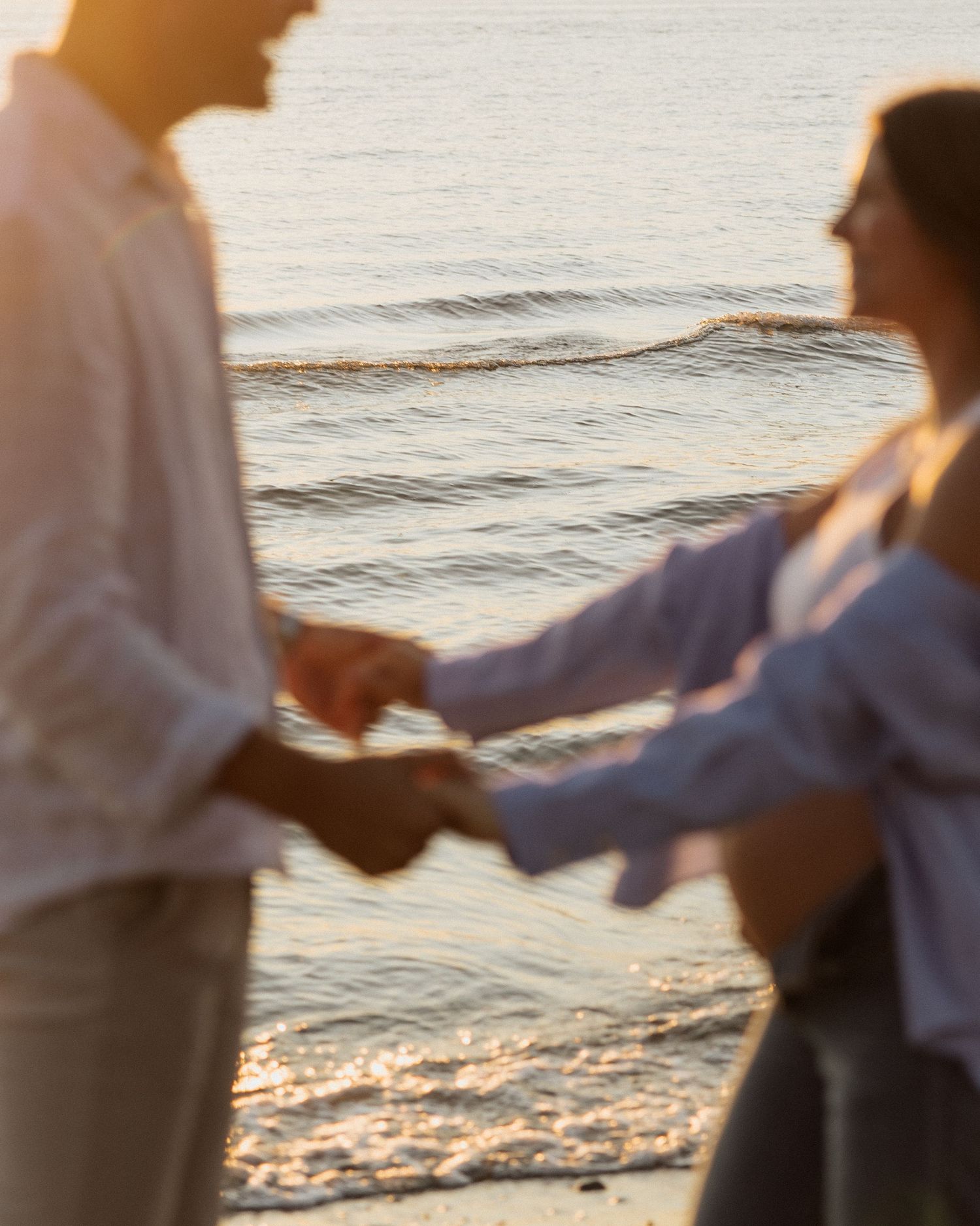 A couple dances together on the beach during a romantic sunset.