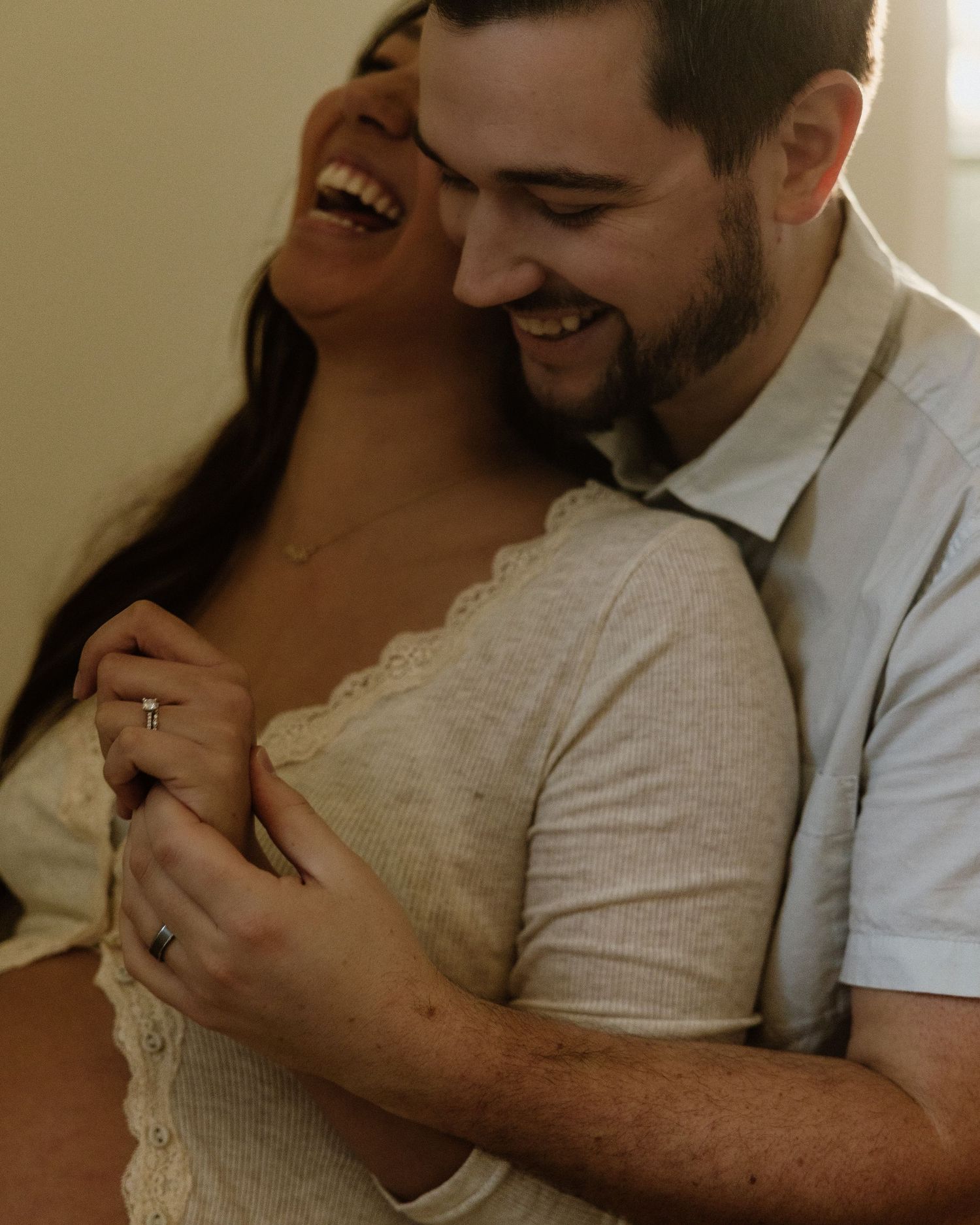 A tender intimate moment between a joyful couple embracing in warm lighting.