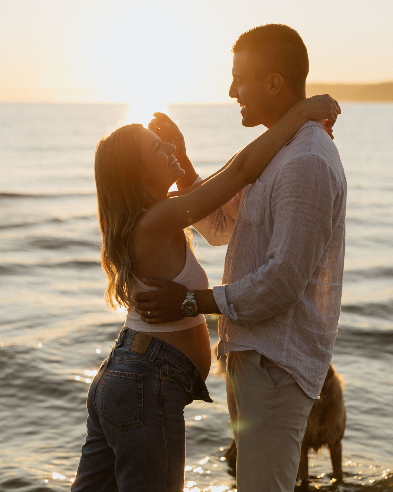 Couple shares loving moment on beach with golden sunset backdrop.