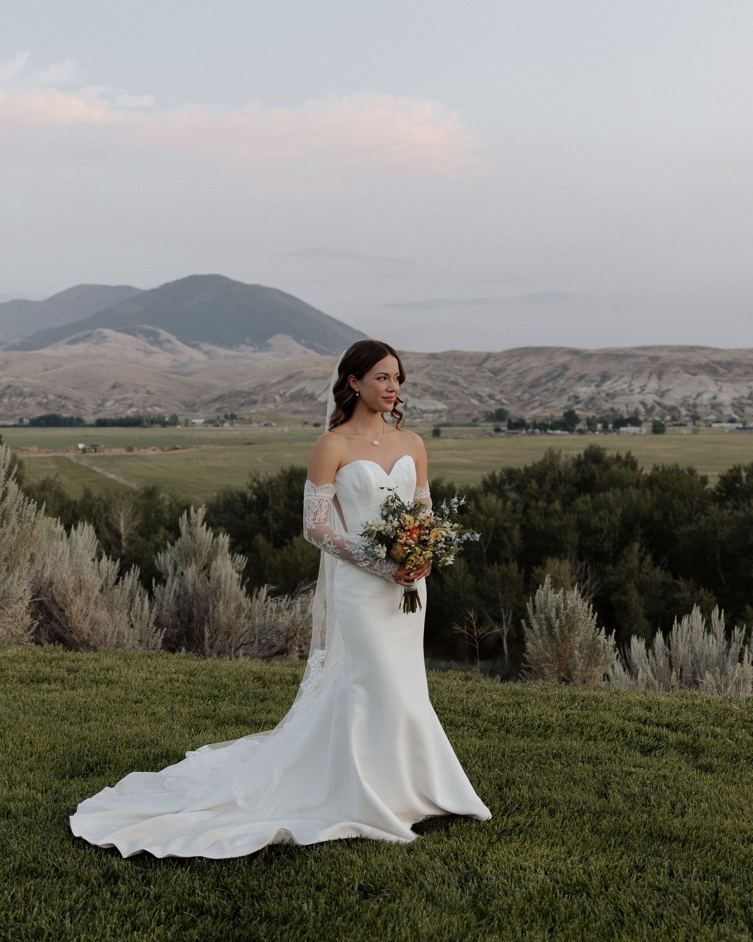A bridal portrait with mountain backdrop showcasing an elegant white wedding gown and autumn bouquet.