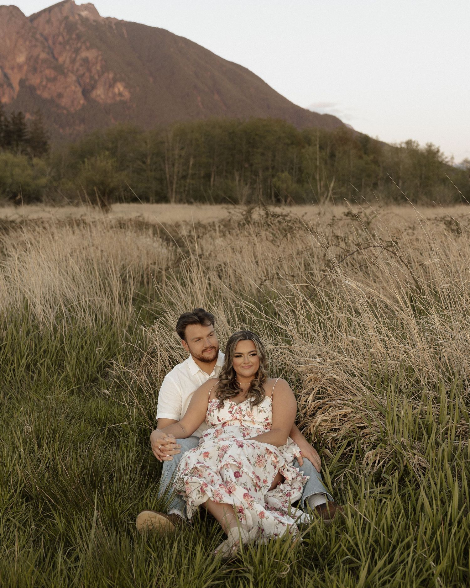 Couple sitting in wilderness with dramatic mountain peaks at dusk.