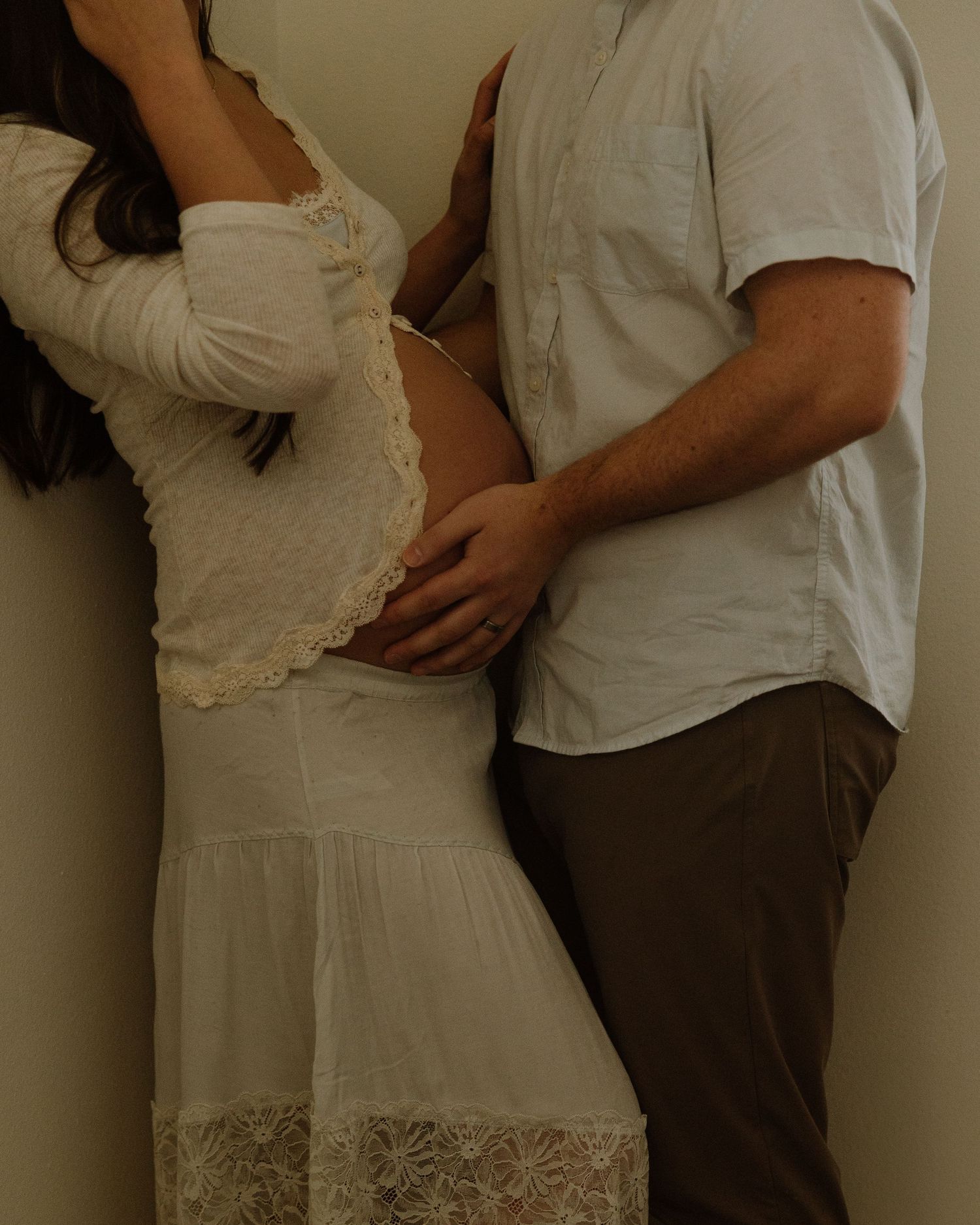 A romantic maternity portrait showing tender affection in a corner of a room.