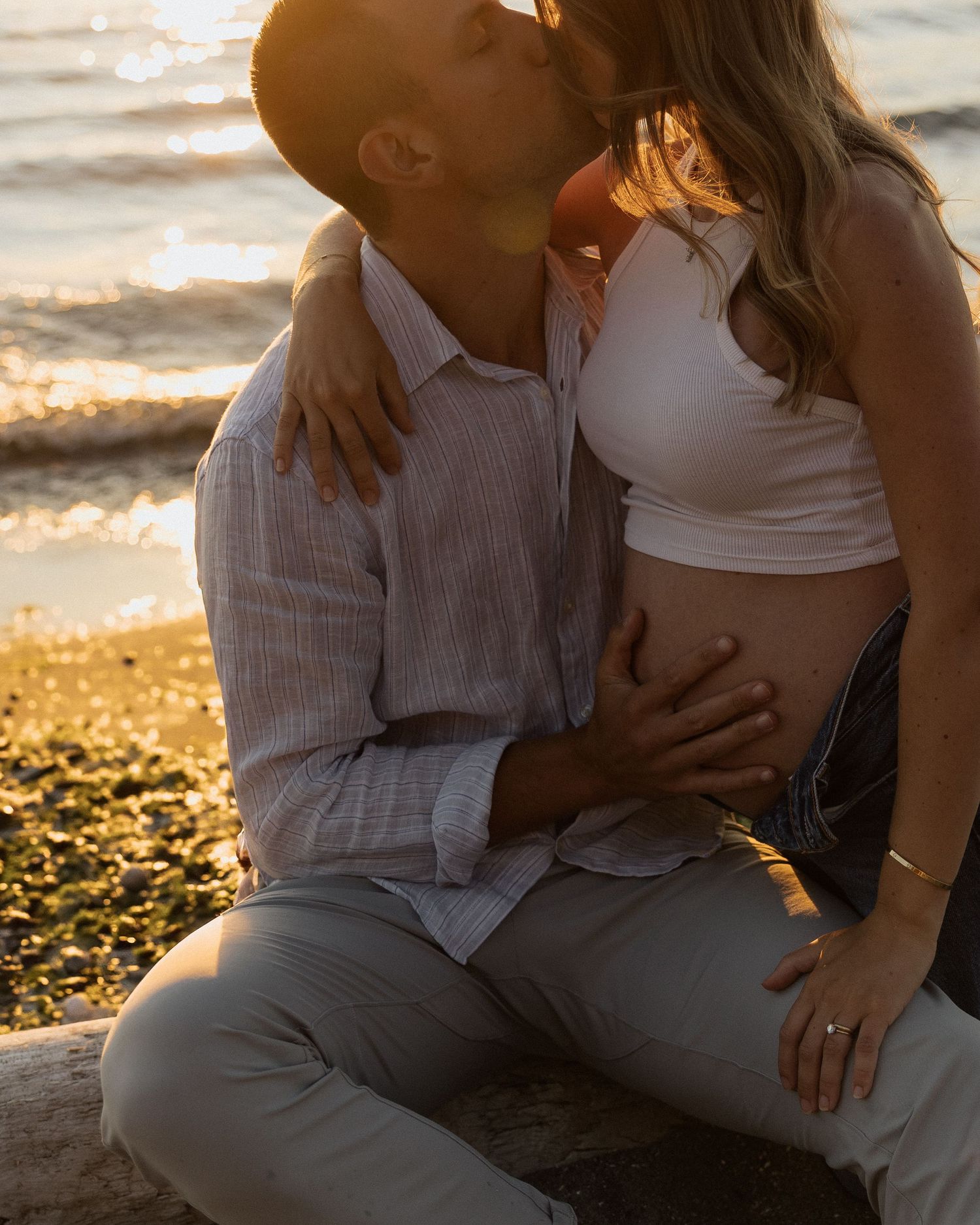 Intimate couple sharing a romantic moment at sunset on a beach shoreline.