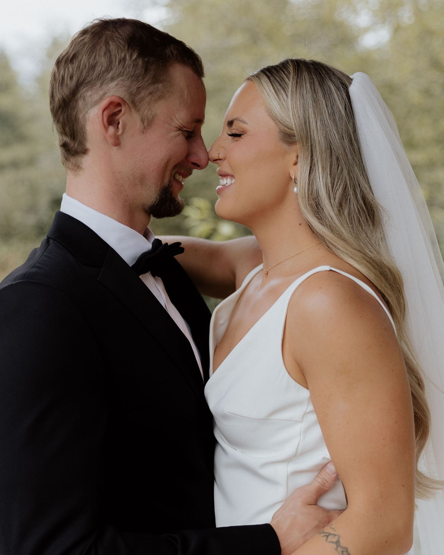Bride and groom share tender moment during outdoor wedding photoshoot.