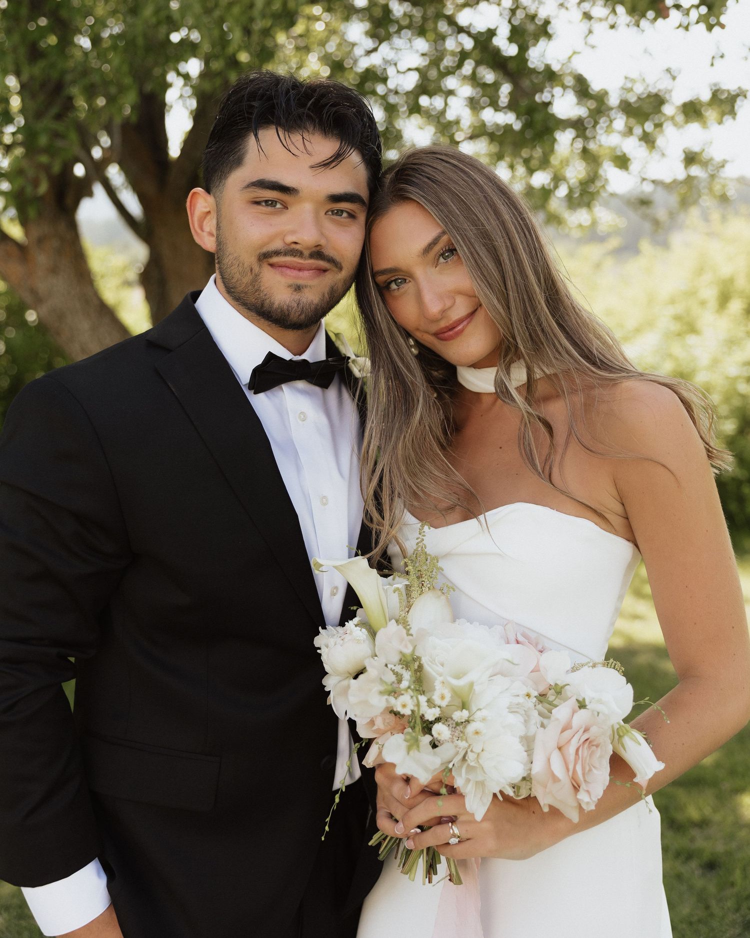Close-up shots of newlyweds posing together outdoors with white floral bouquet.