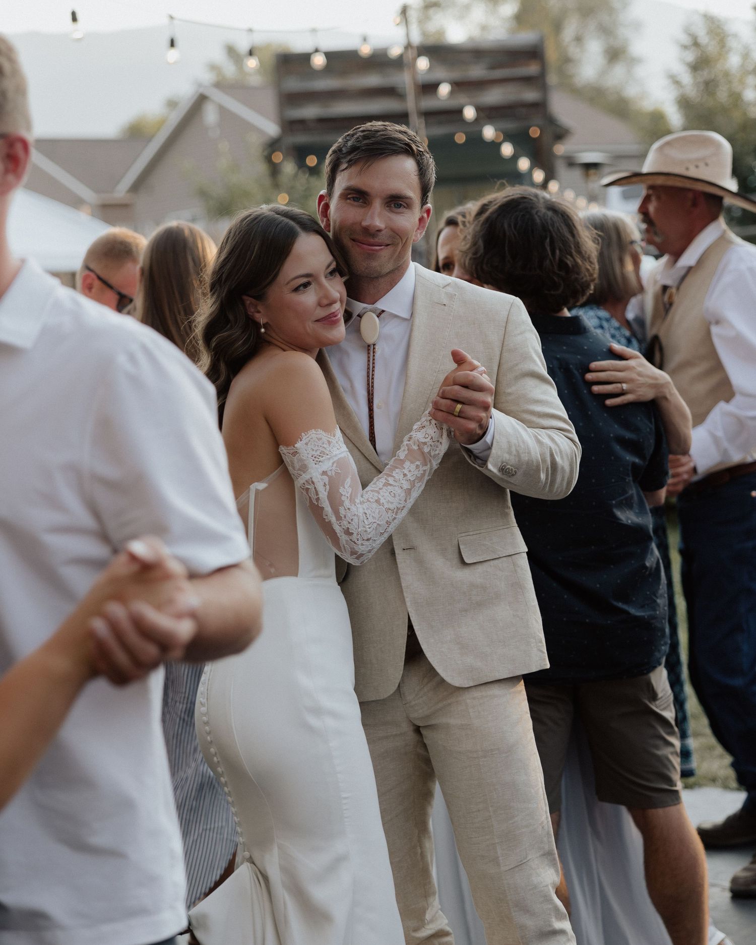 Wedding couple dancing together at their outdoor reception surrounded by guests.