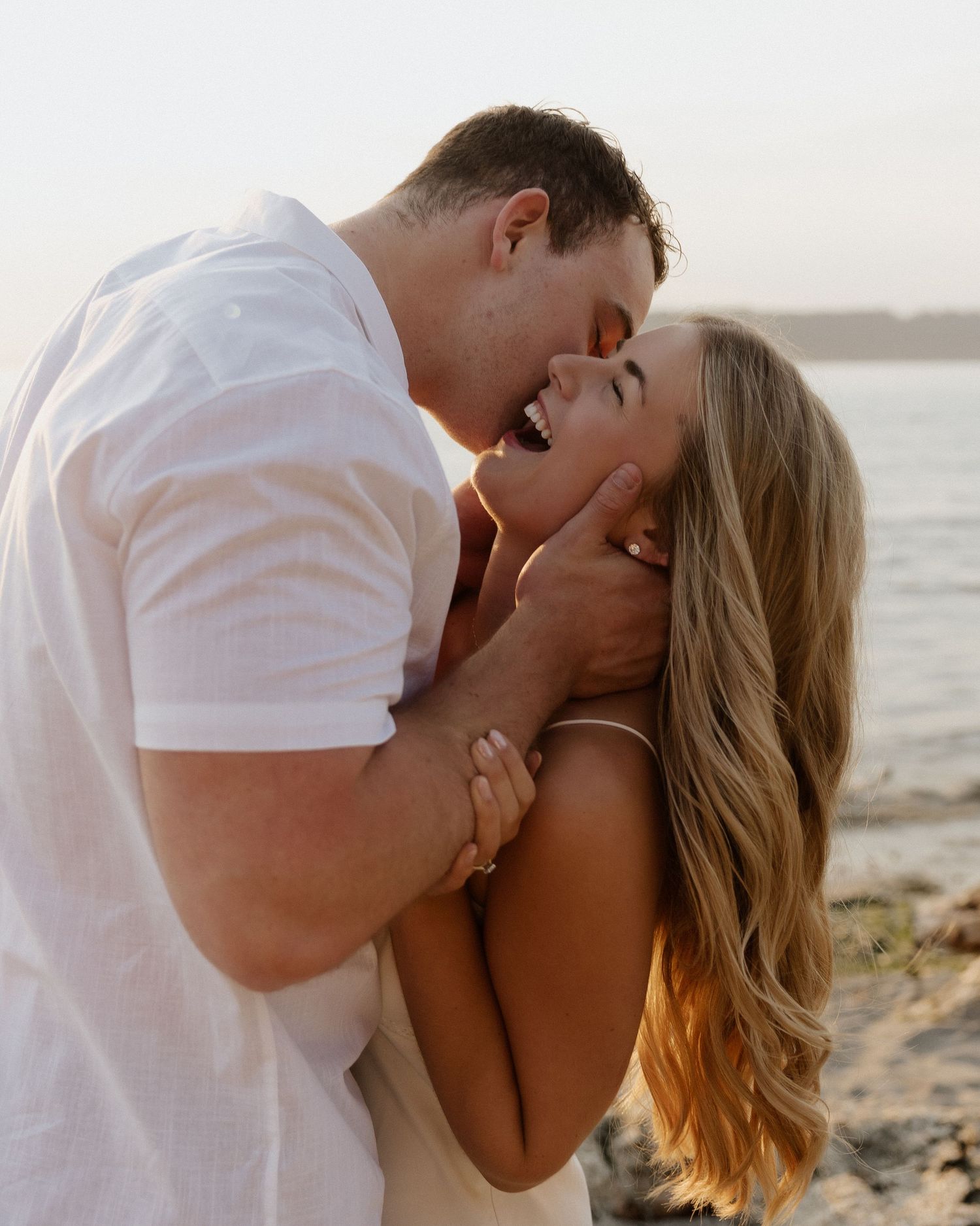 An intimate moment between a couple embracing on a beach during golden hour.