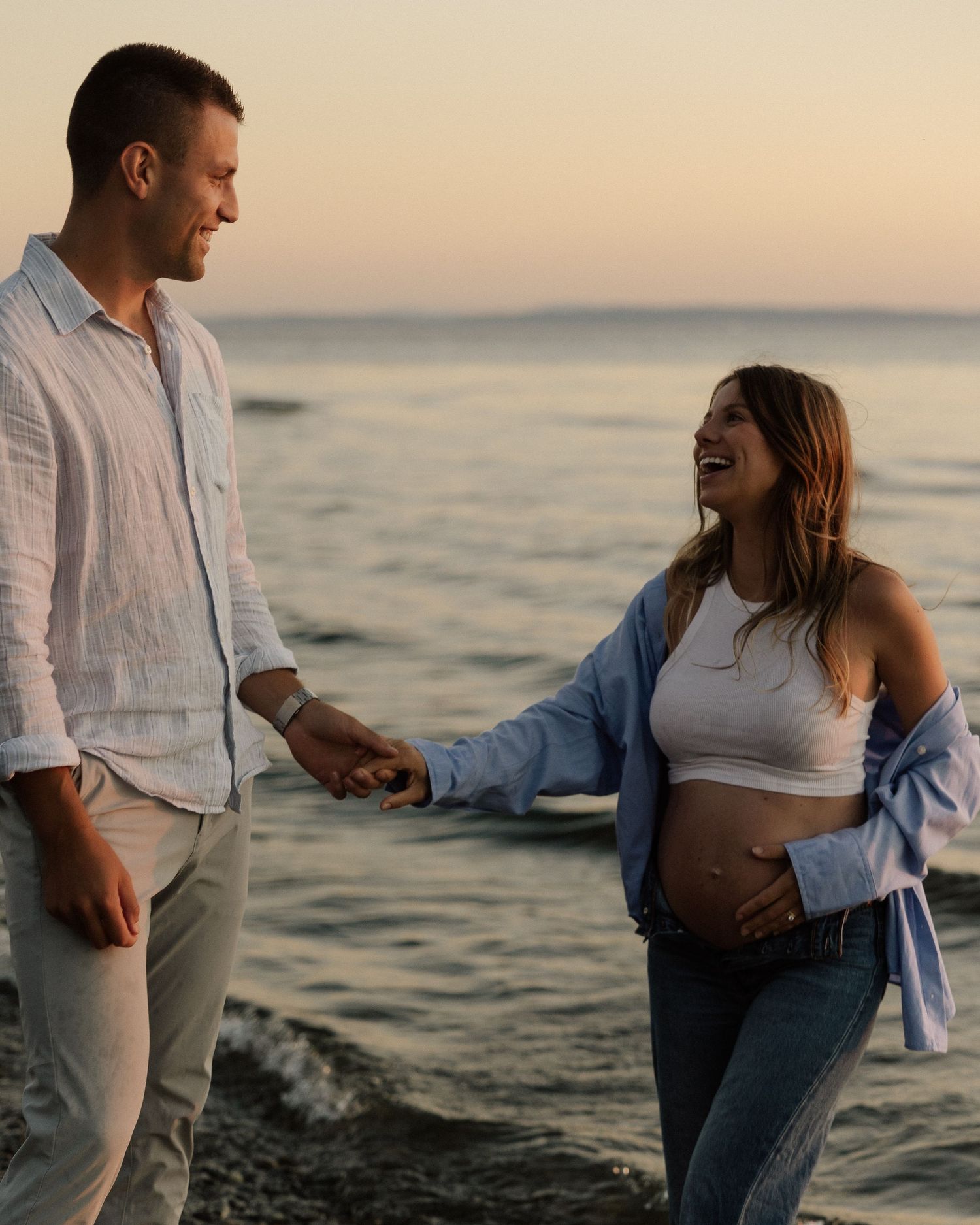 A couple shares a joyful moment on the beach during golden hour.