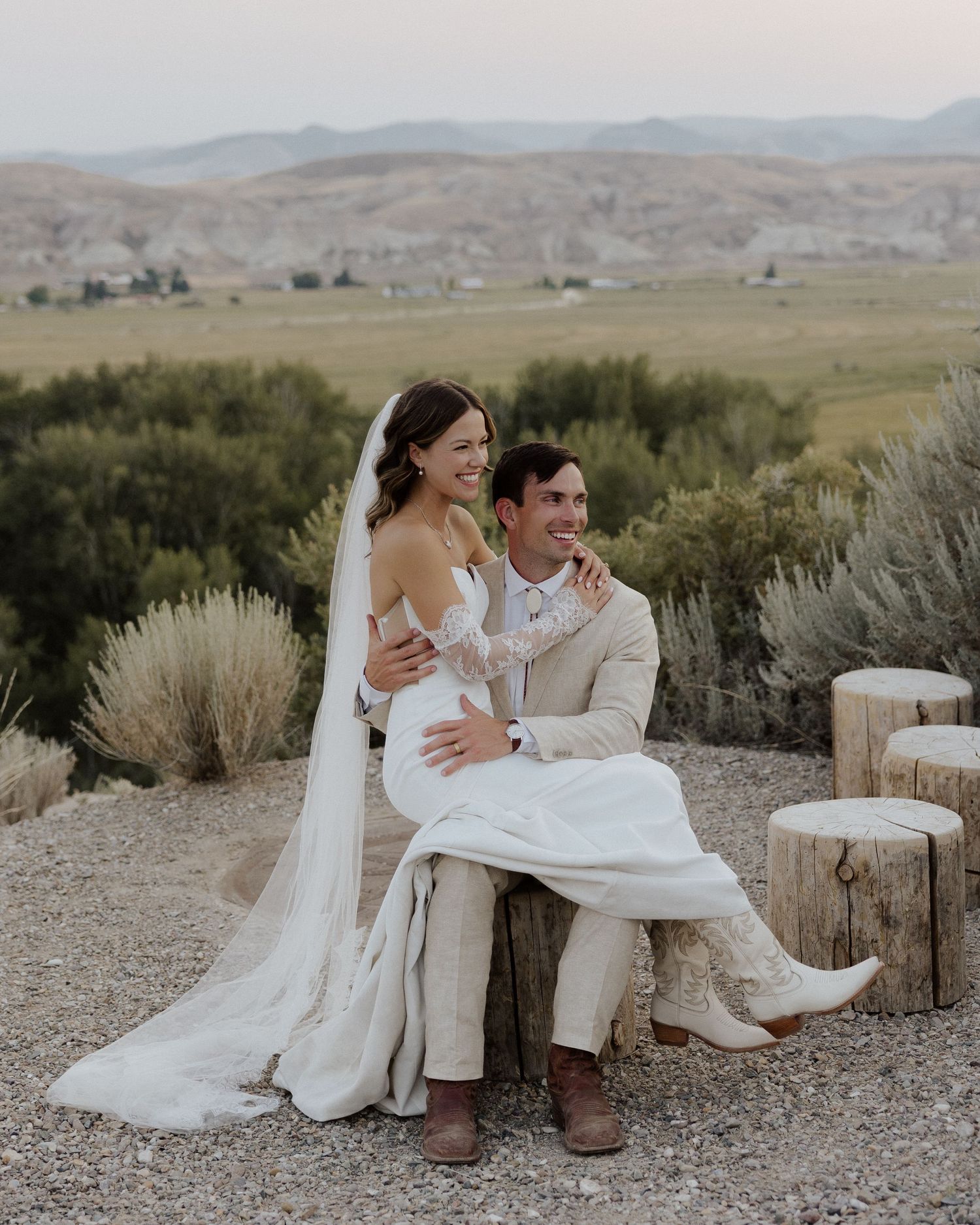 Couple shares an intimate moment on rustic wooden logs with a scenic mountain backdrop.
