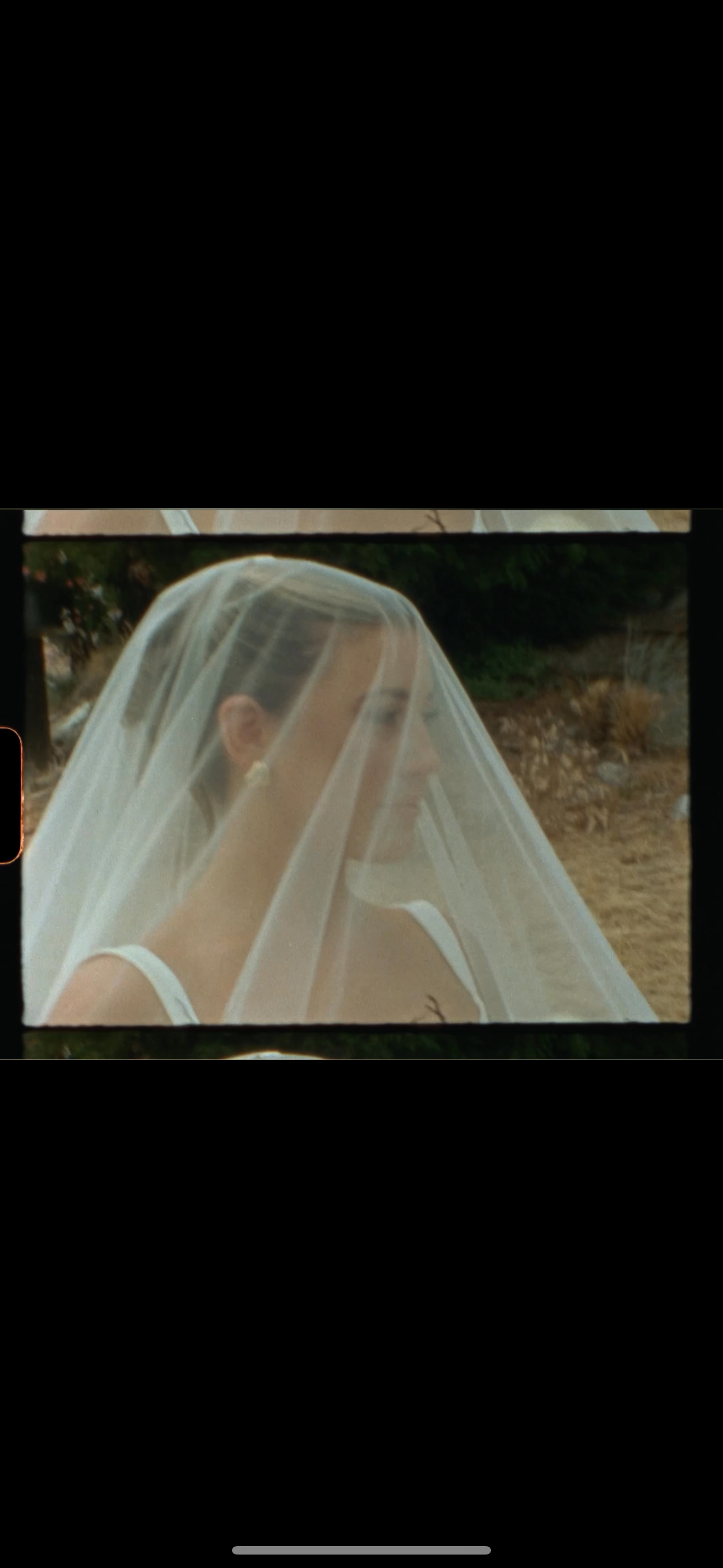 Close-up view of a bride wearing a delicate tulle veil against a dark background.