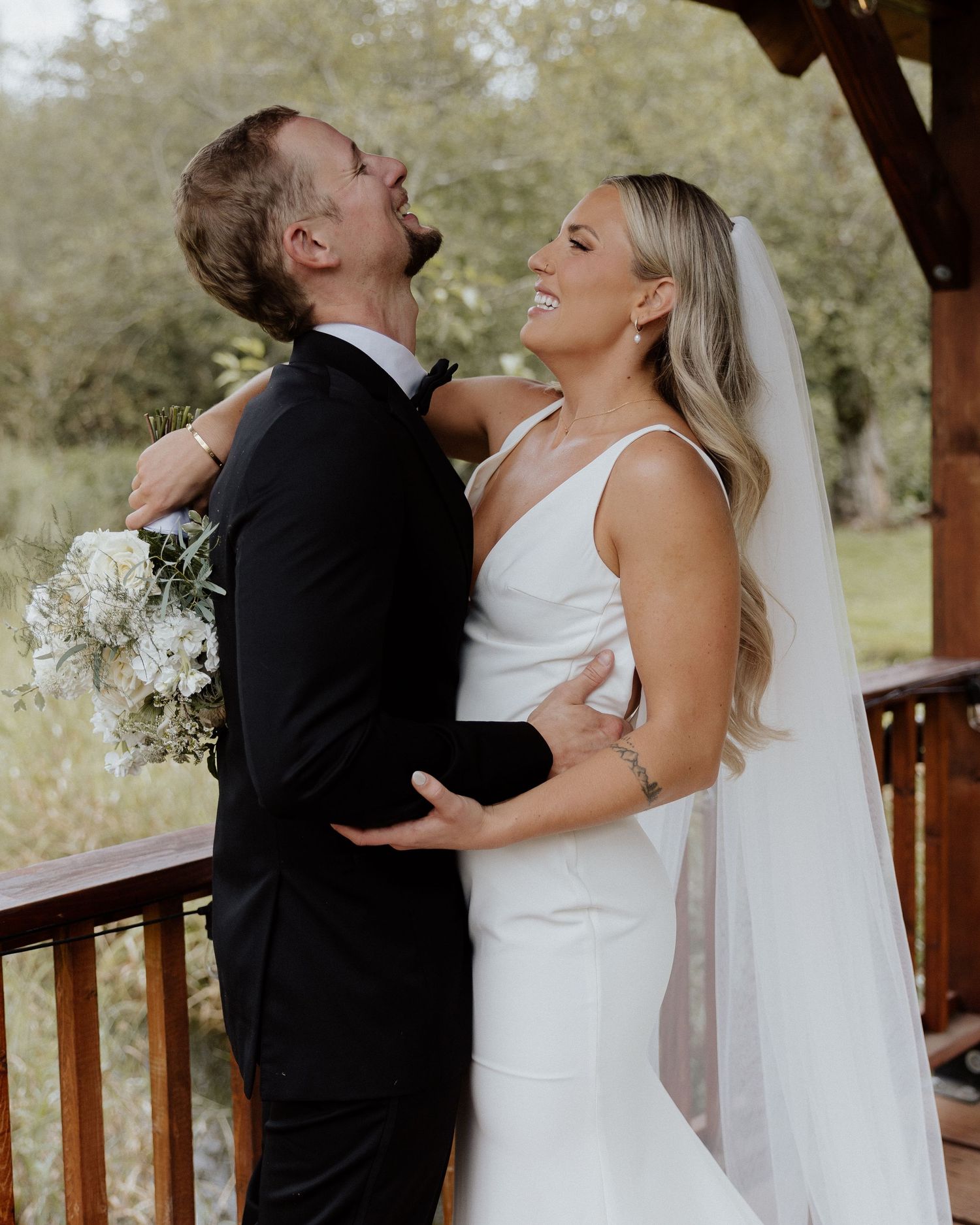 Joyful couple laughing together during their outdoor wedding portraits.