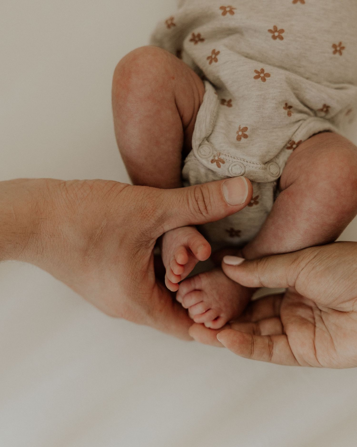 Close-up of tiny newborn feet being gently held in parent's hands.