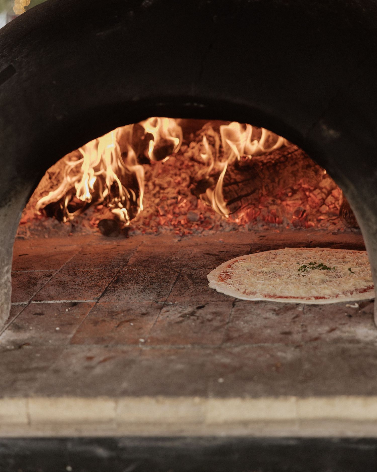 Flames roaring inside a brick pizza oven with stone cooking surface.