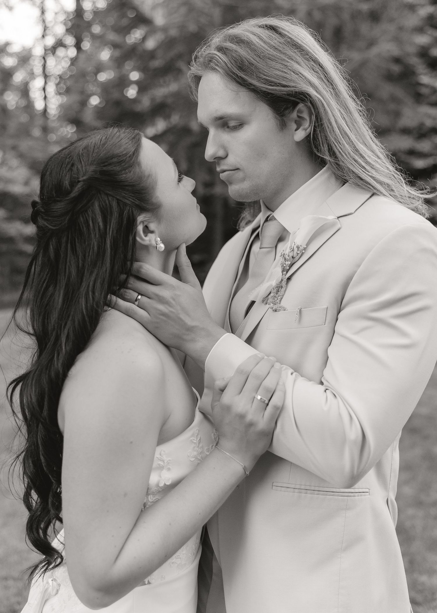 Black and white portrait of bride and groom sharing intimate moment outdoors.
