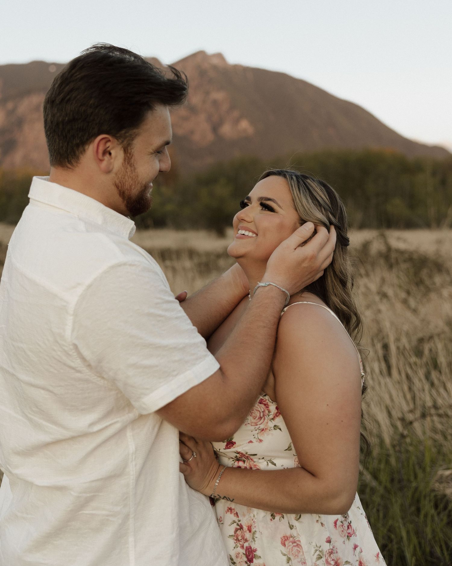 Romantic couple shares tender moment against mountain backdrop.